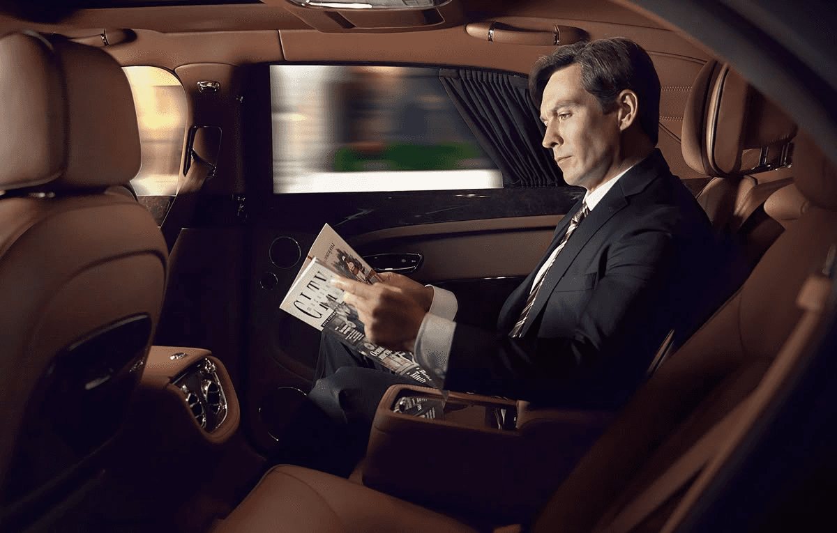 un homme d'affaire lisant le journal à l'arriere d'une voiture