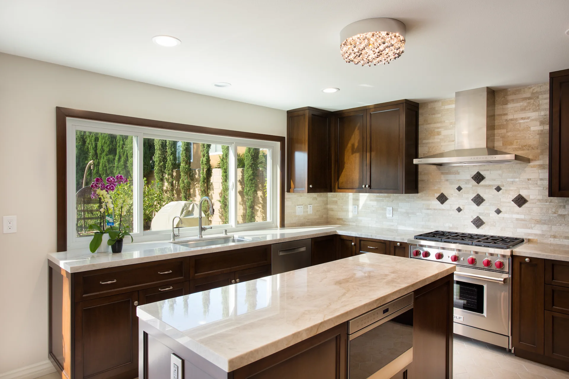 Contemporary kitchen with dark wood cabinets, patterned tile backsplash, and quartz island in Orange Interior Remodel.