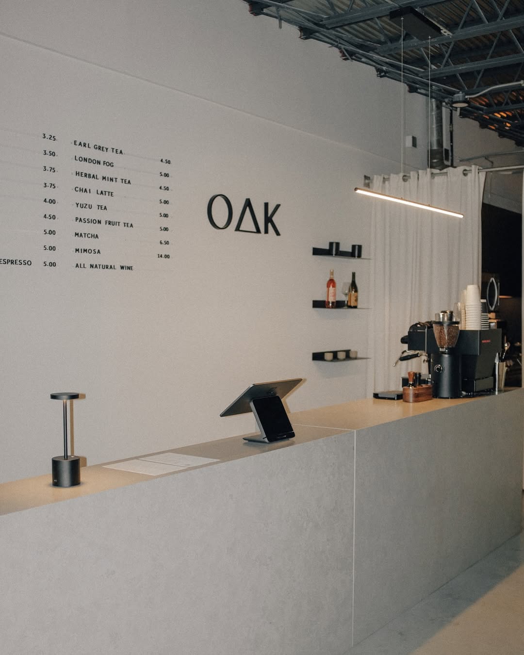 Concrete café counter with dimensional OAK logo signage inside Oak & Saint coffee and wine bar.