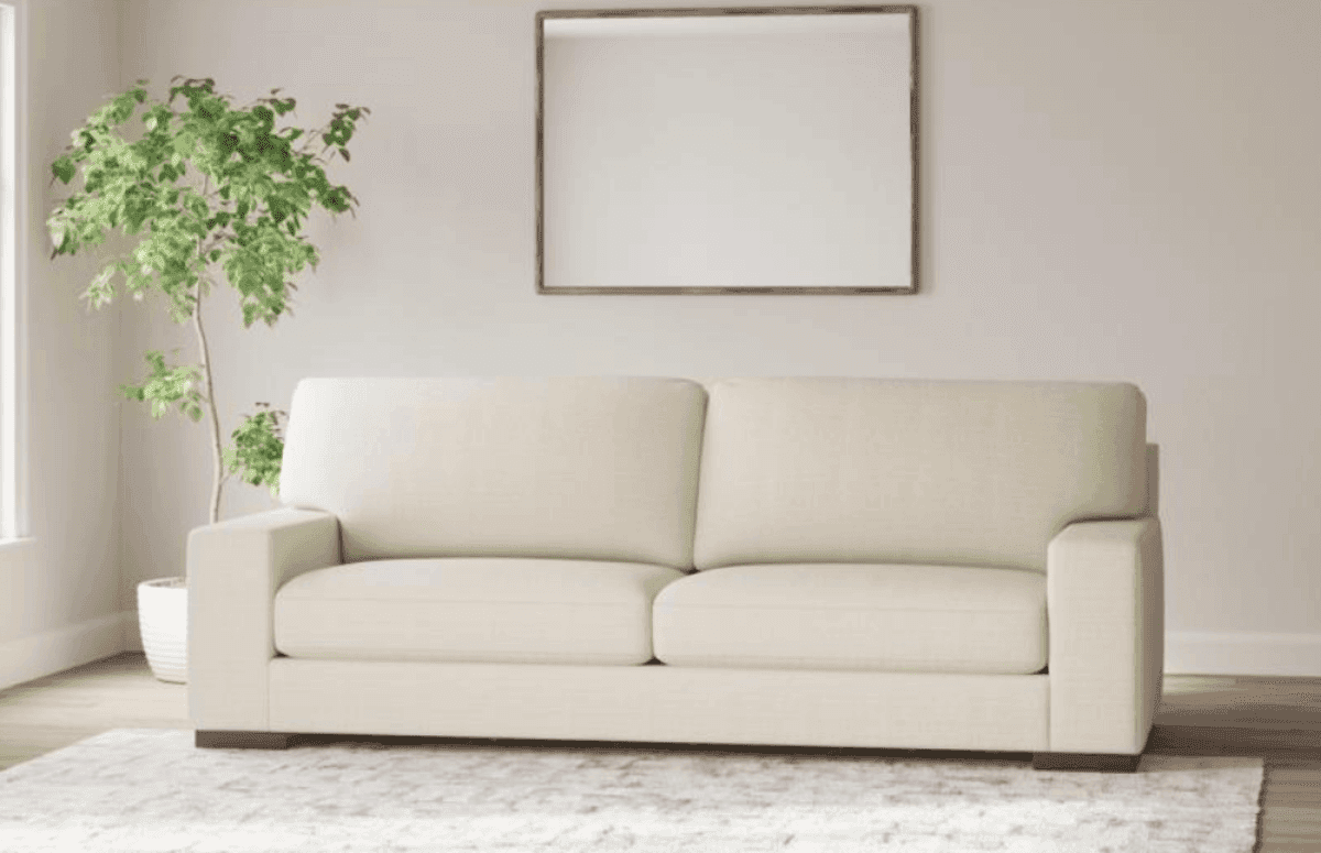 Cream Ashley Furniture sofa in a bright room with a plant and wall mirror