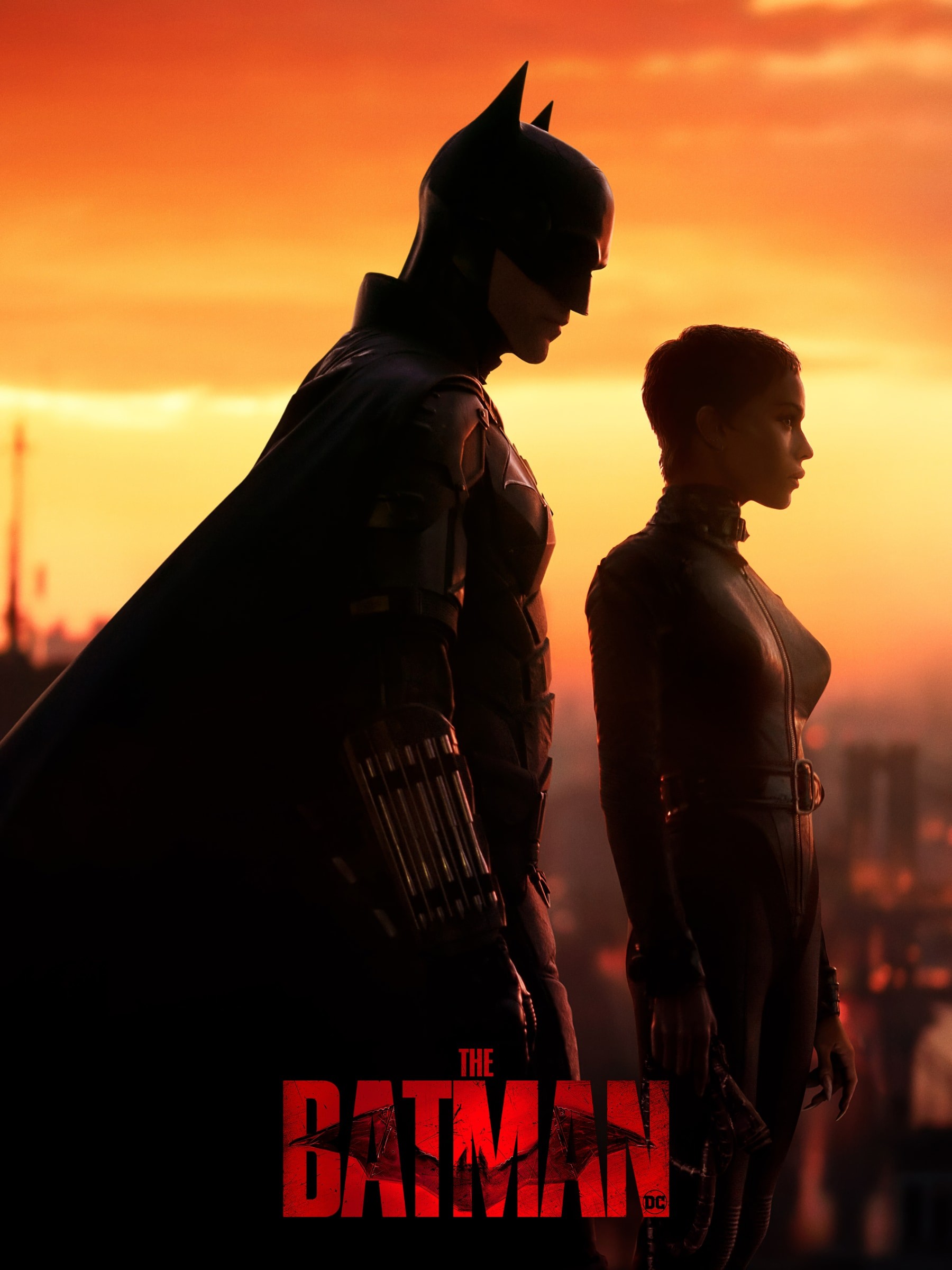 Batman and Catwoman stand side by side at sunset over a city skyline, movie title “The Batman.”