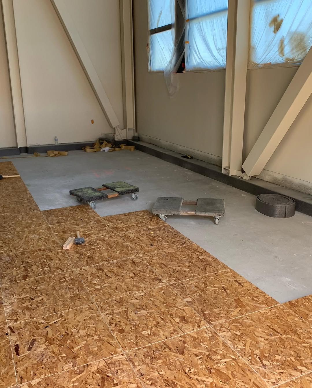 Plywood underlayment covering the floor ahead of the acoustic layer