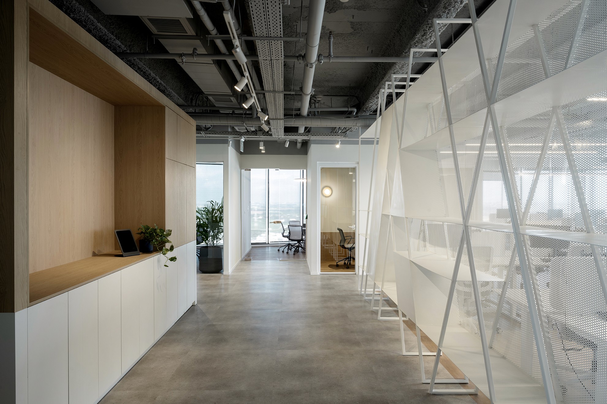 ציר התנועה המרכזי במשרד: מצד אחד חיפוי קיר נגרות פונקציונלי ומצד שני אלמנט הספרייה ממתכת המפריד את עמדות העבודה