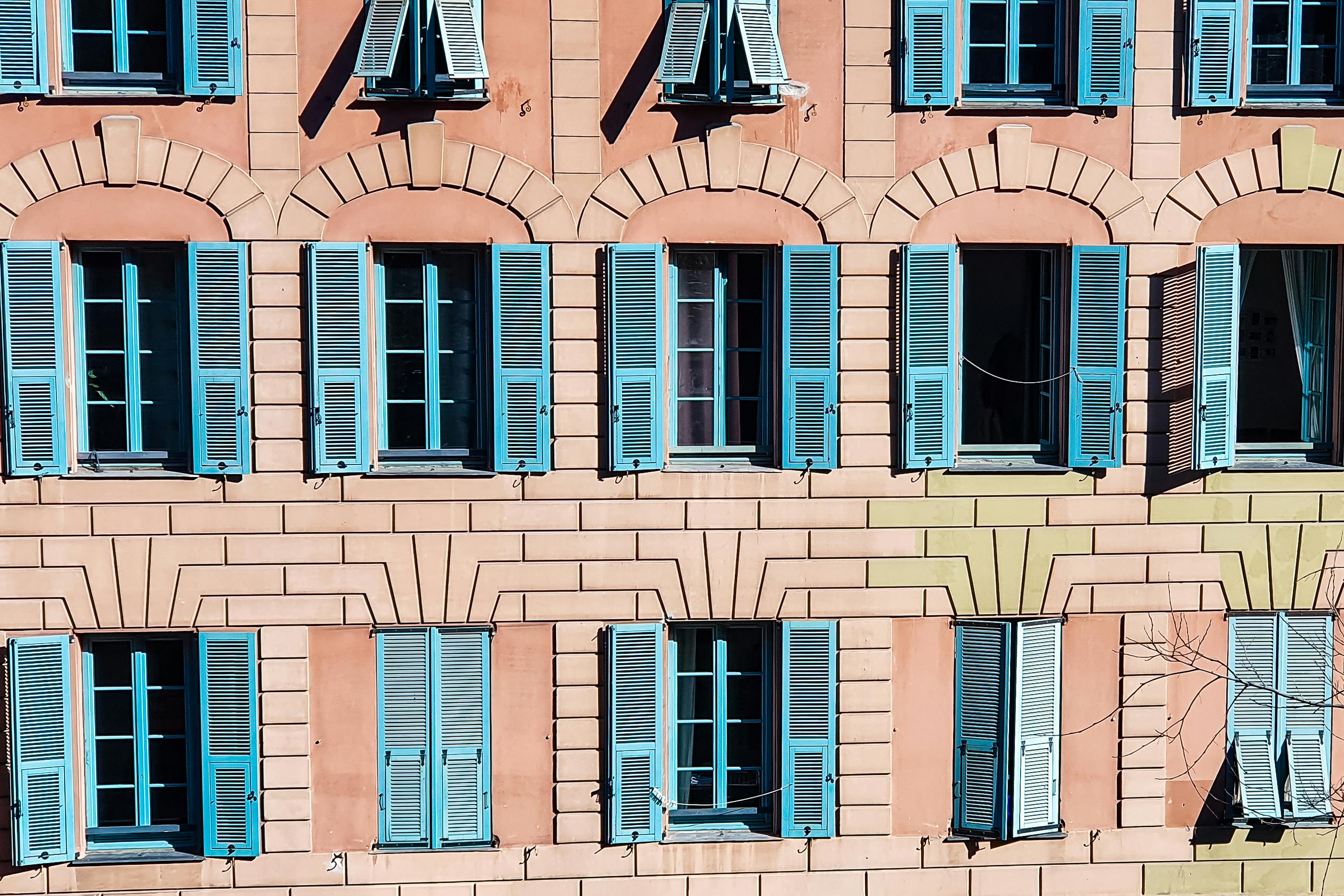 Façade d'un immeuble rose aux fenêtres bleues à Nice
