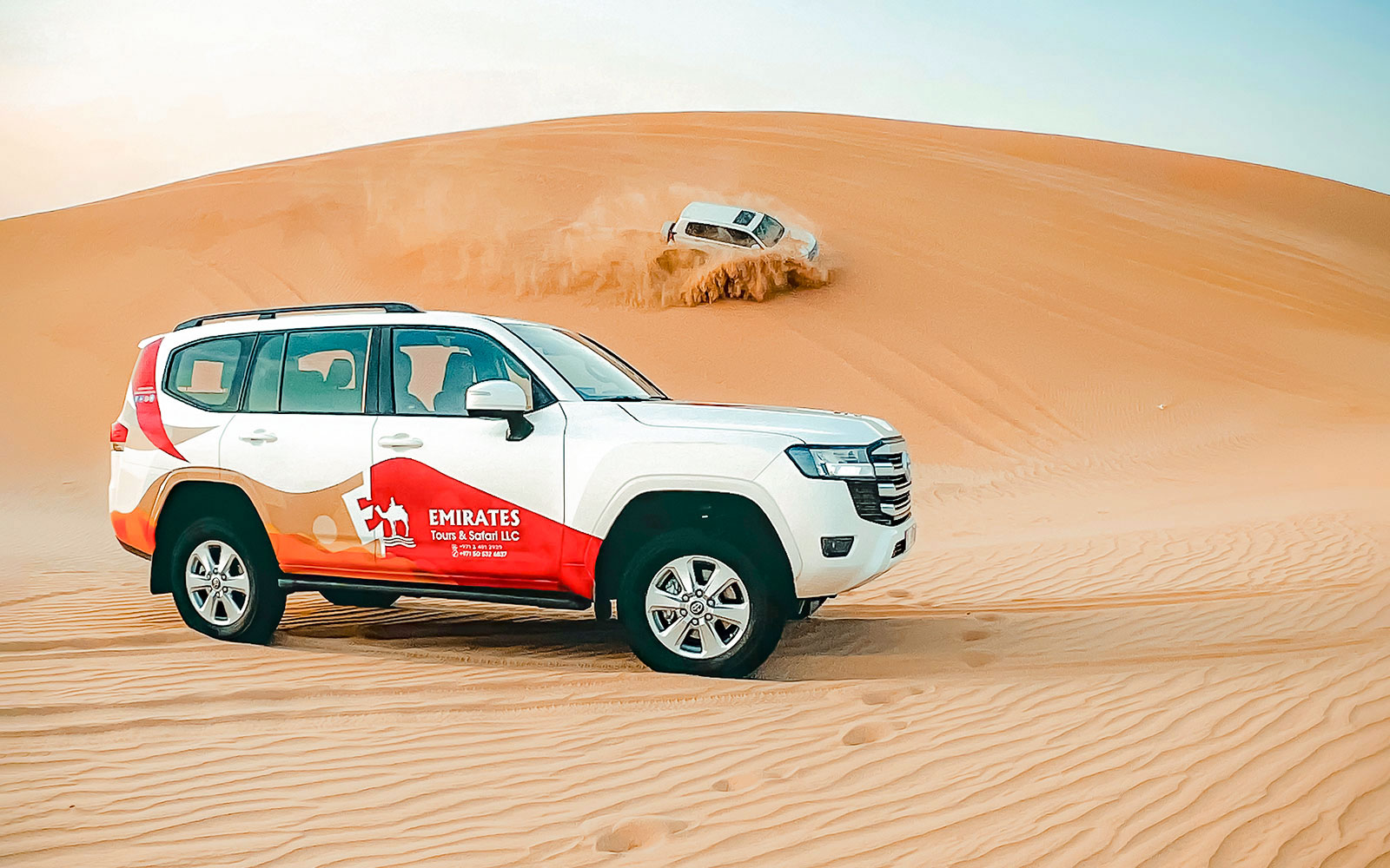 SUVs roulant sur les dunes de sable lors d'un safari désert de nuit à Abu Dhabi.