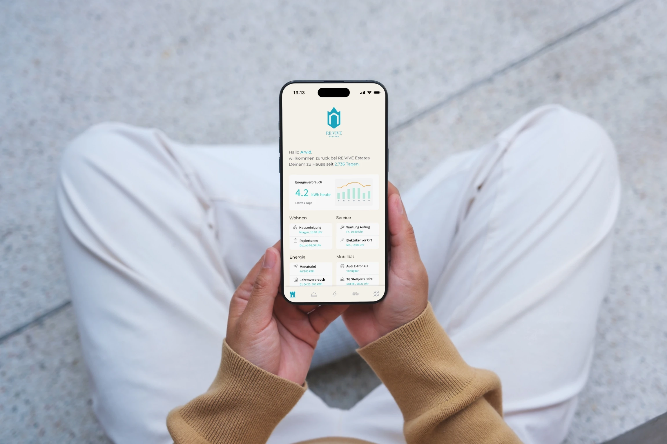 Person hält ein Smartphone mit der RE:VIVE-Estates-App, die Energieverbrauch, Services und Mobilitätsangebote eines digital vernetzten Wohnkonzepts übersichtlich darstellt.