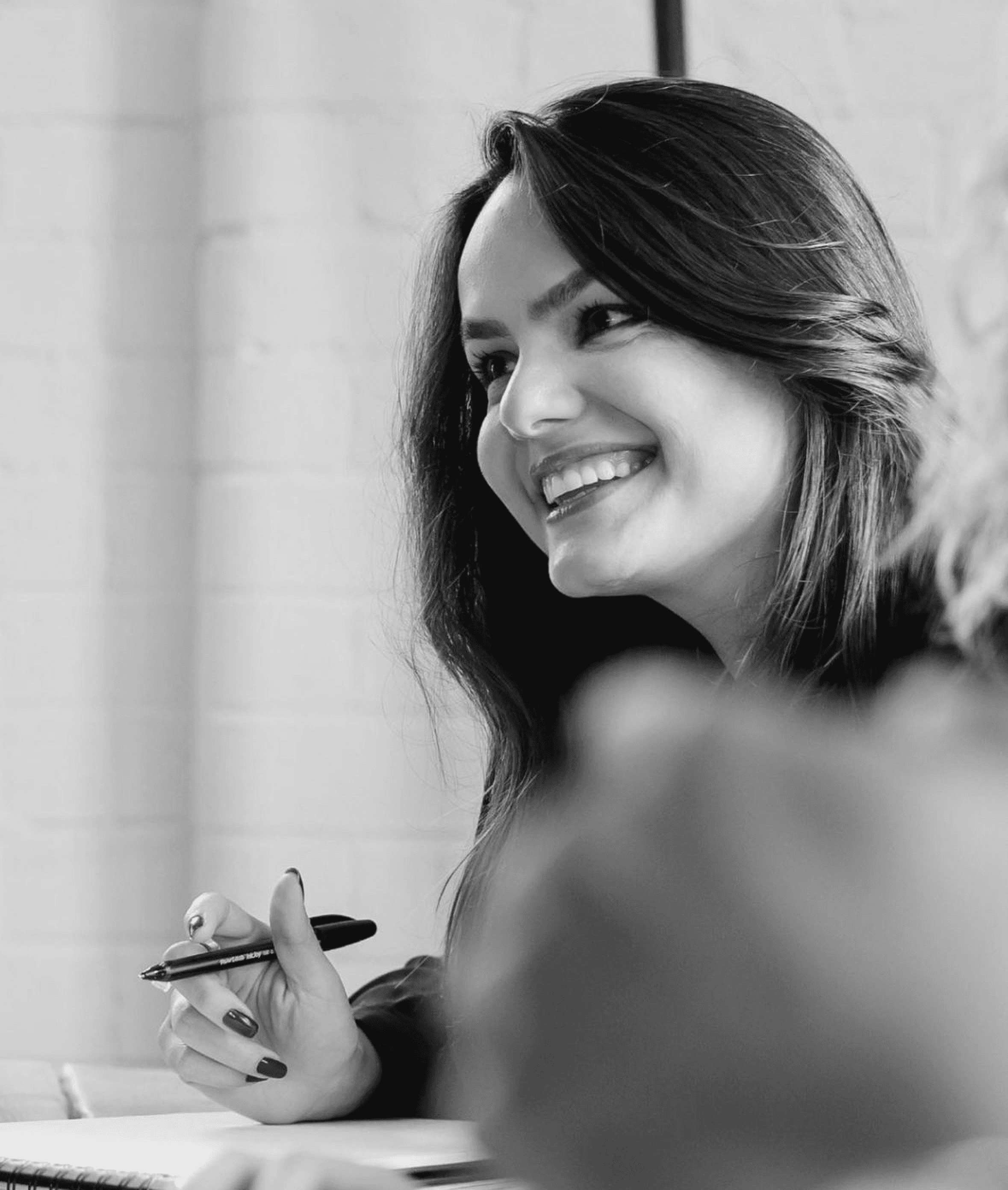 Black and white photo of two people looking at a computer screen with papers on wall