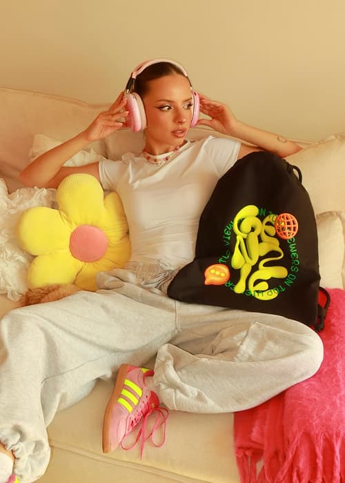 Three young women pose playfully against a vibrant green background, each holding colorful snacks.
