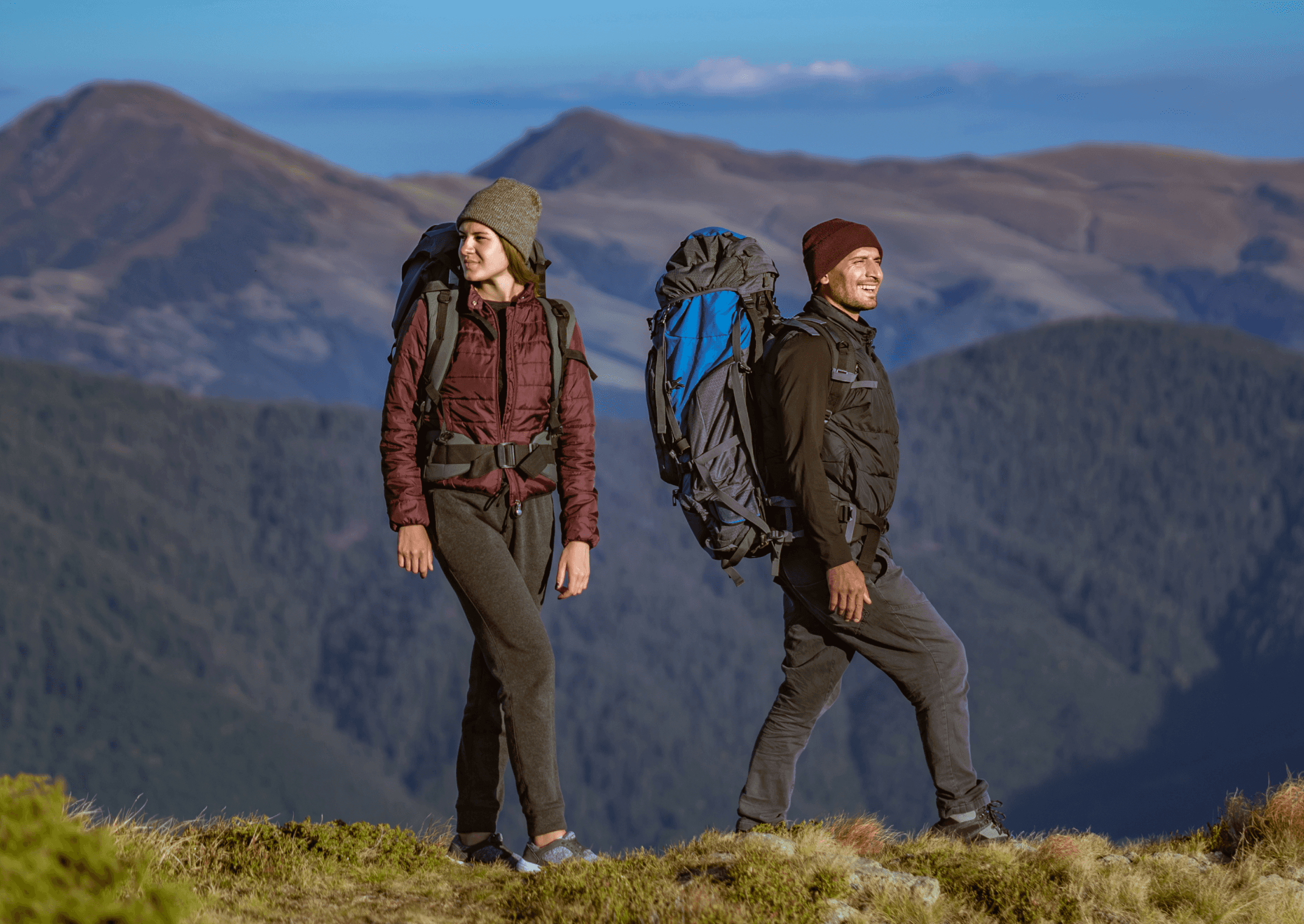 Two hikers with backpacks walking in the mountains.