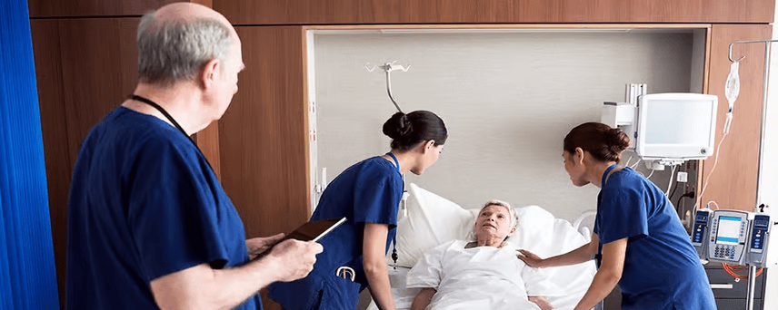 Nurses assisting a patient in a hospital bed while a doctor observes.