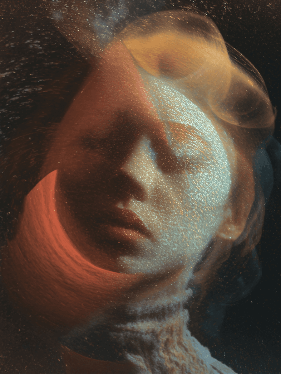 Artistic portrait of a person with eyes closed, surrounded by swirling golden and red light effects that create a dreamlike, ethereal atmosphere.