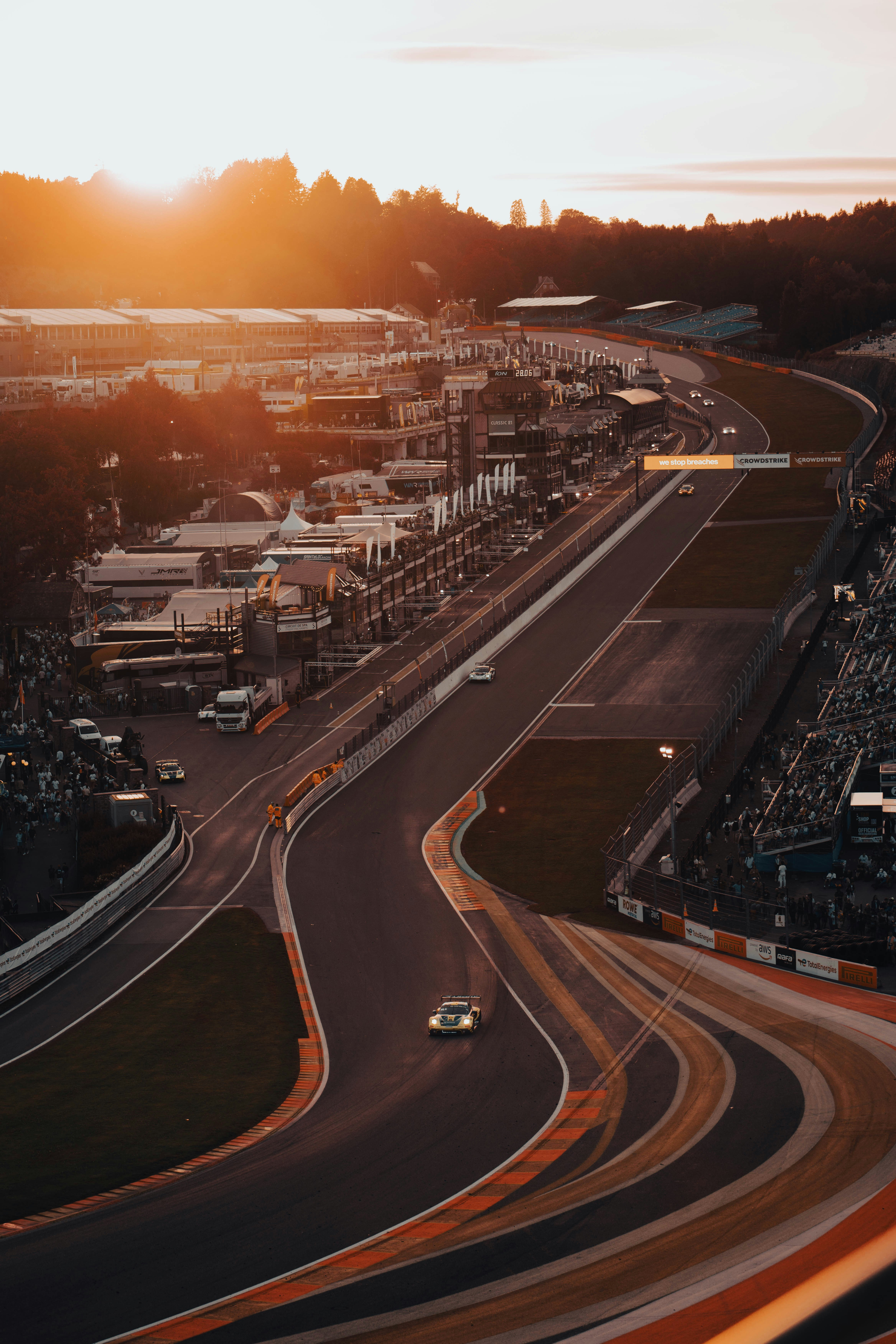 Sunset over a race track with cars and spectators