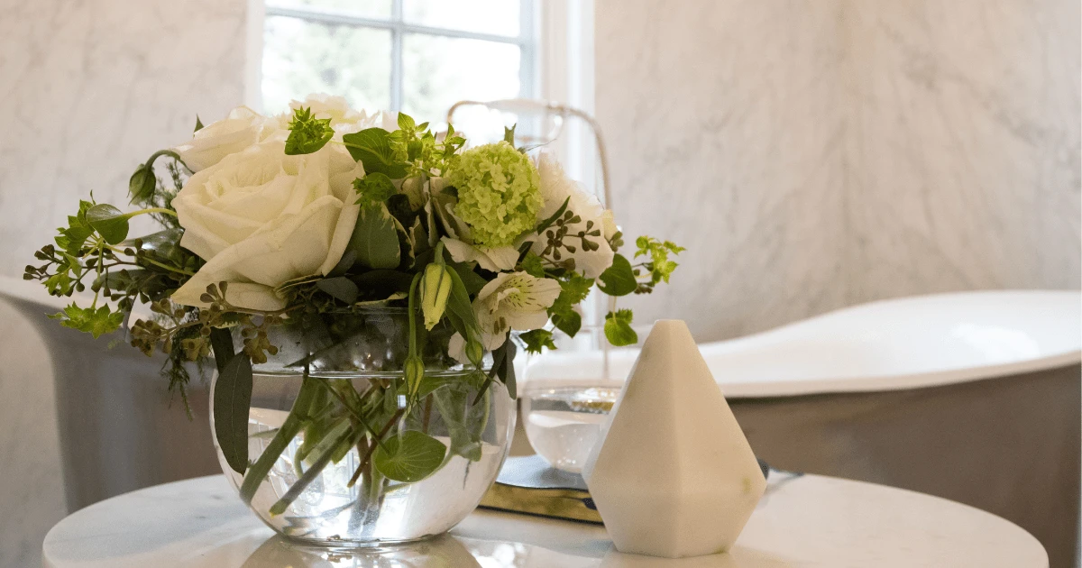 Image of Luxury home design featuring a vase with white roses and green flowers on a marble table.