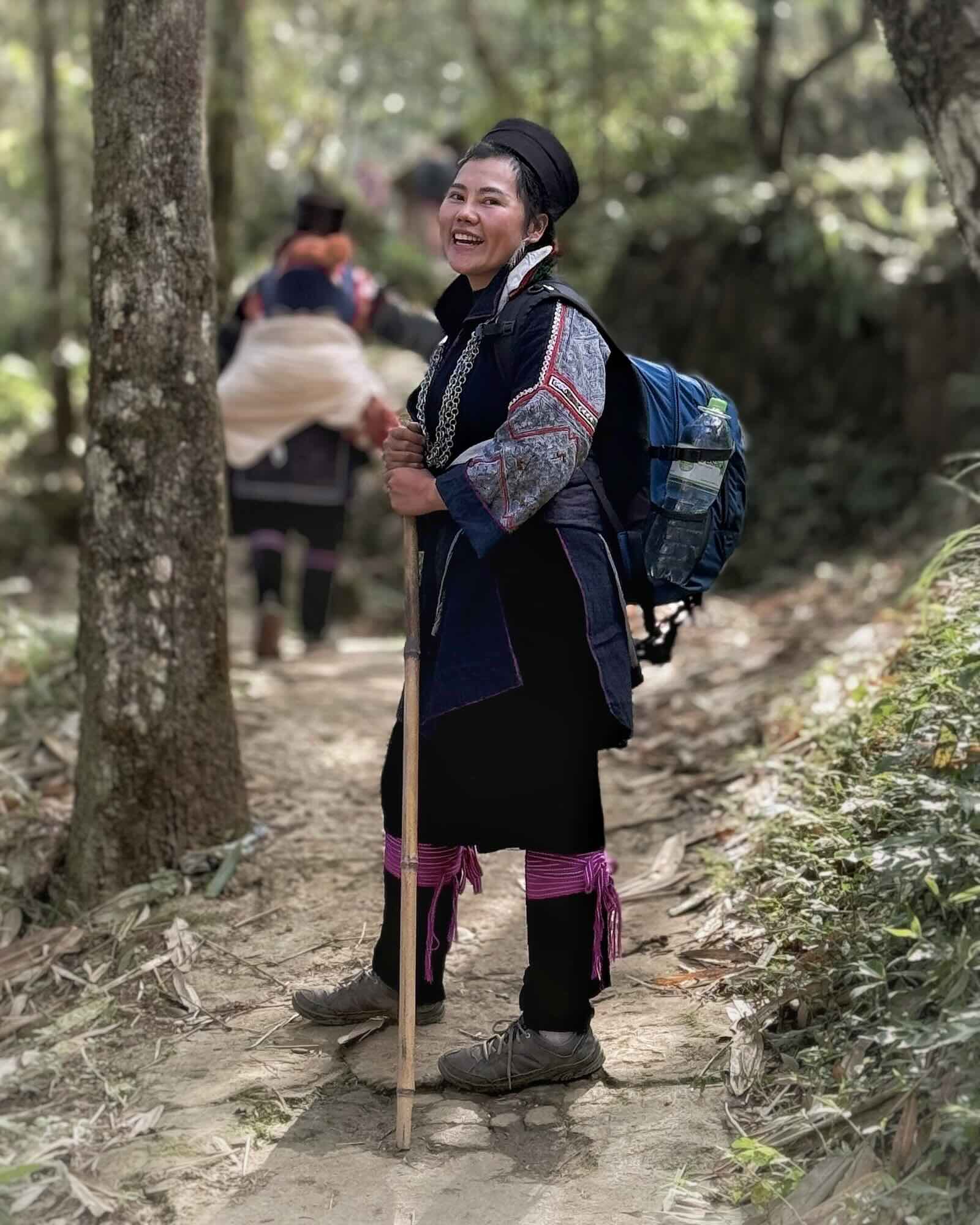 Pang, a Black Hmong trekking guide, smiling on a forest trail near Sapa, Vietnam.