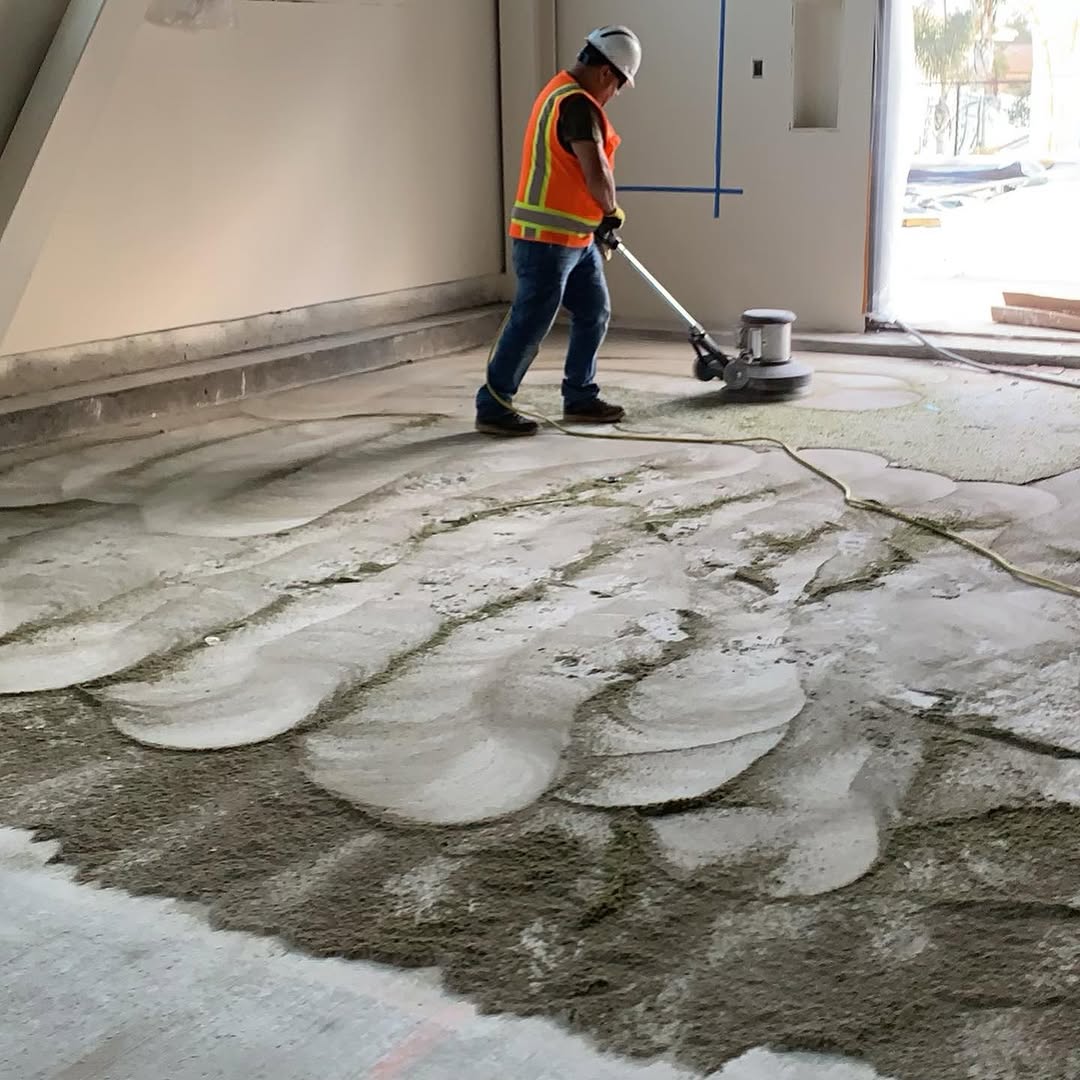 Installer grinding old adhesive off a concrete slab