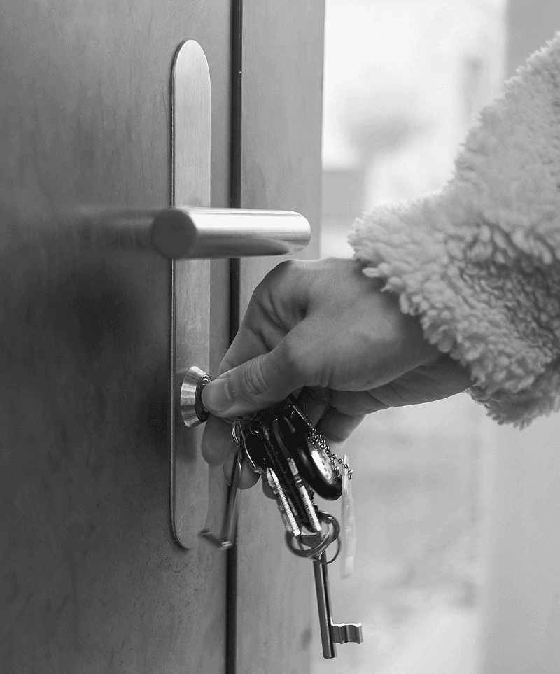 Person locking the front door of a home, representing property transfer and conveyancing services.