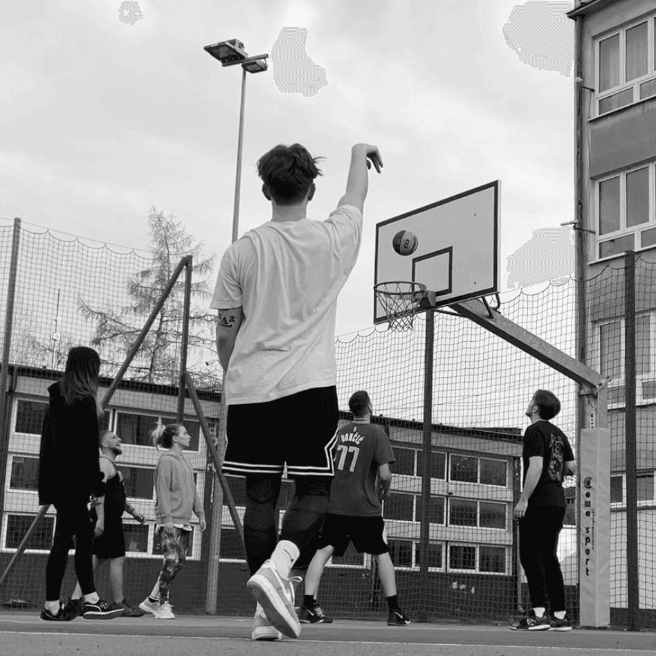 Shot from basketball court. Bartek is staning on the center of the photo after shooting the 3-pointer and waiting for the ball to drop trough the basket.