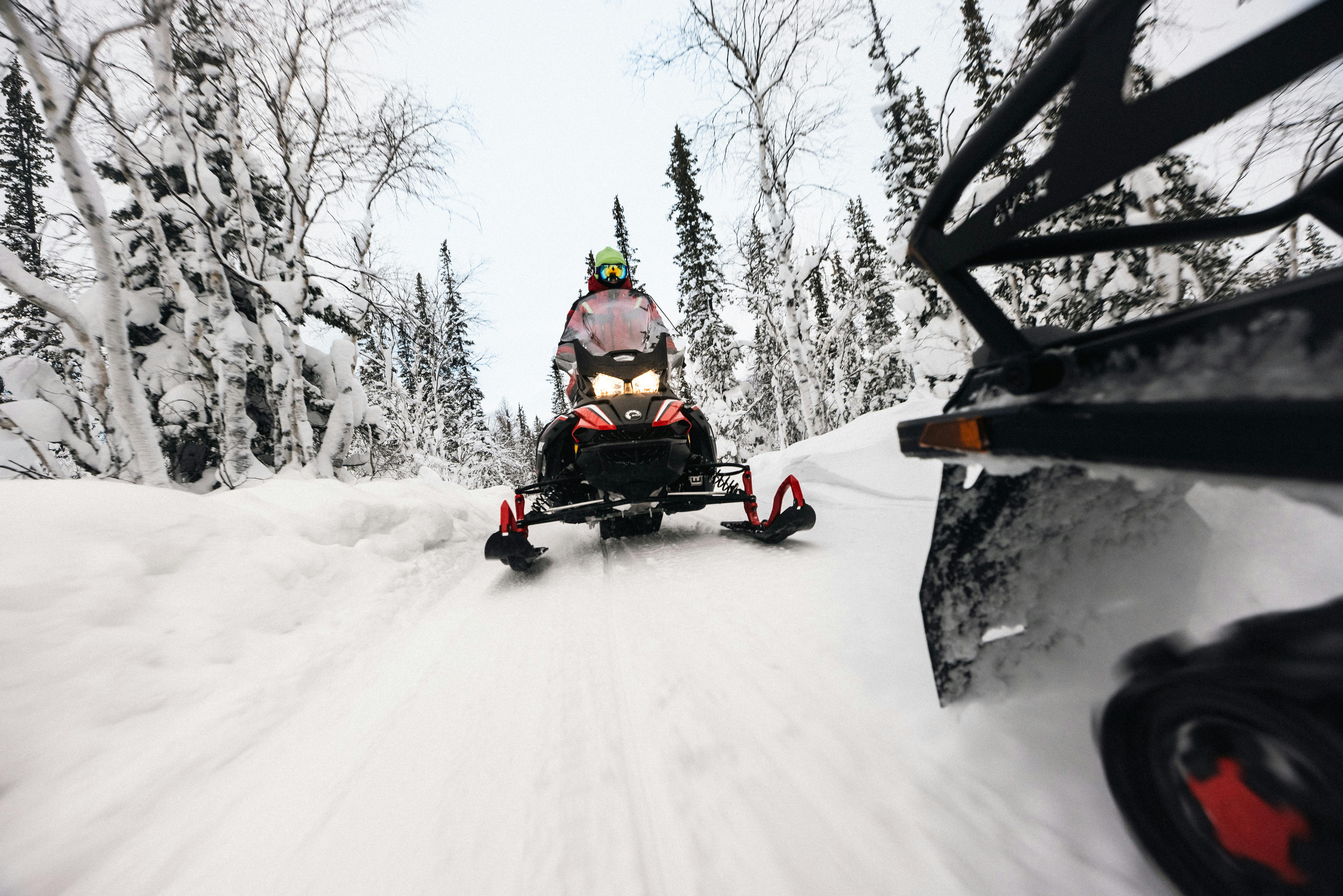 Deux hommes roulent en motoneige sur une piste enneigée