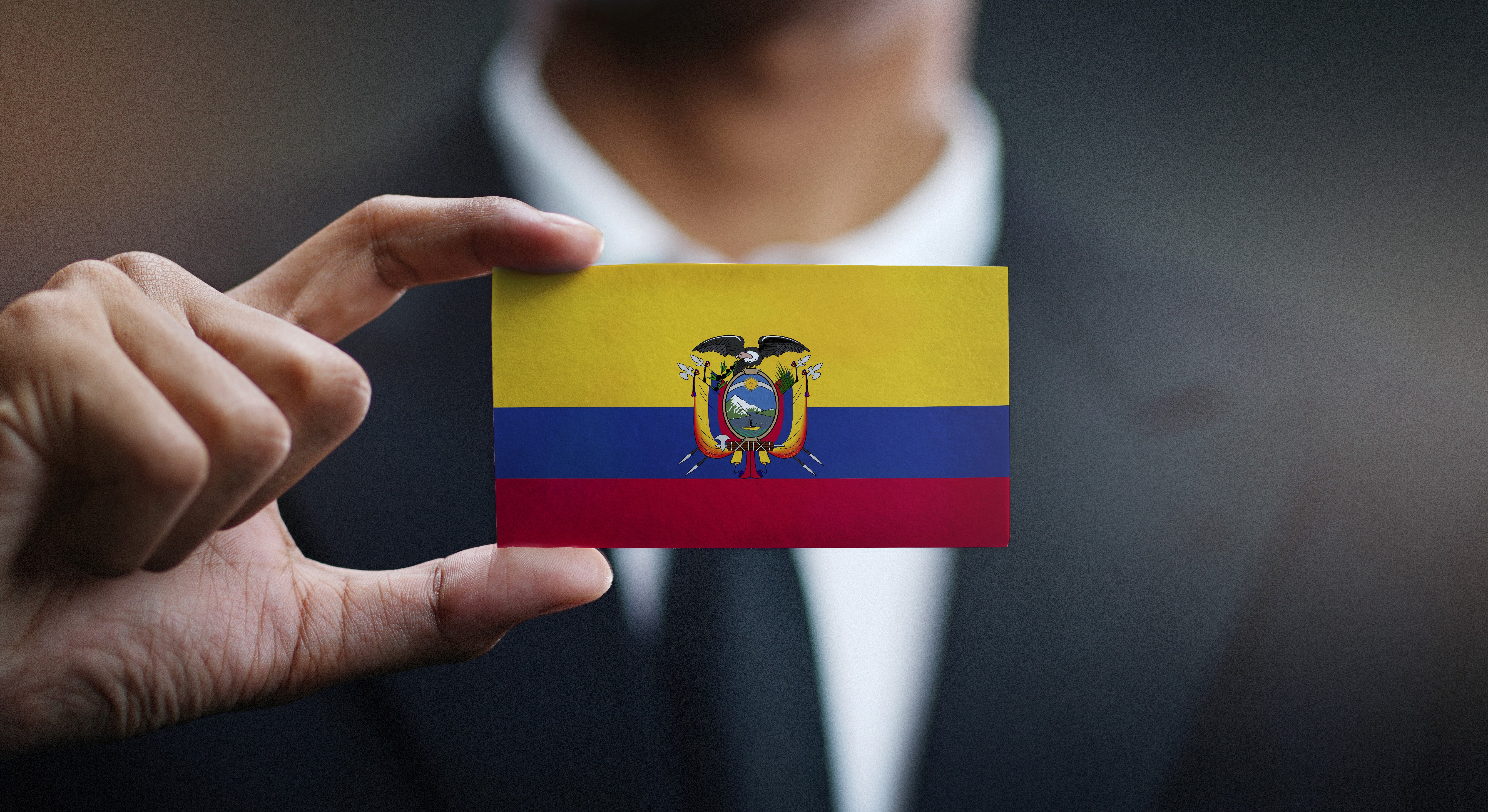 Una persona de negocios sosteniendo una tarjeta con la bandera de Ecuador, simbolizando la identidad o negocios relacionados con este país
