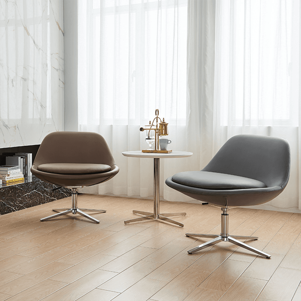 Contemporary swivel accent chairs duo: burnt orange tan leather and charcoal gray leather, curved pod design, plush cushions, polished chrome star swivel bases, paired with minimalist white round table on chrome pedestal, stylish modern living room setup with marble walls, sheer curtains, natural light, wood flooring