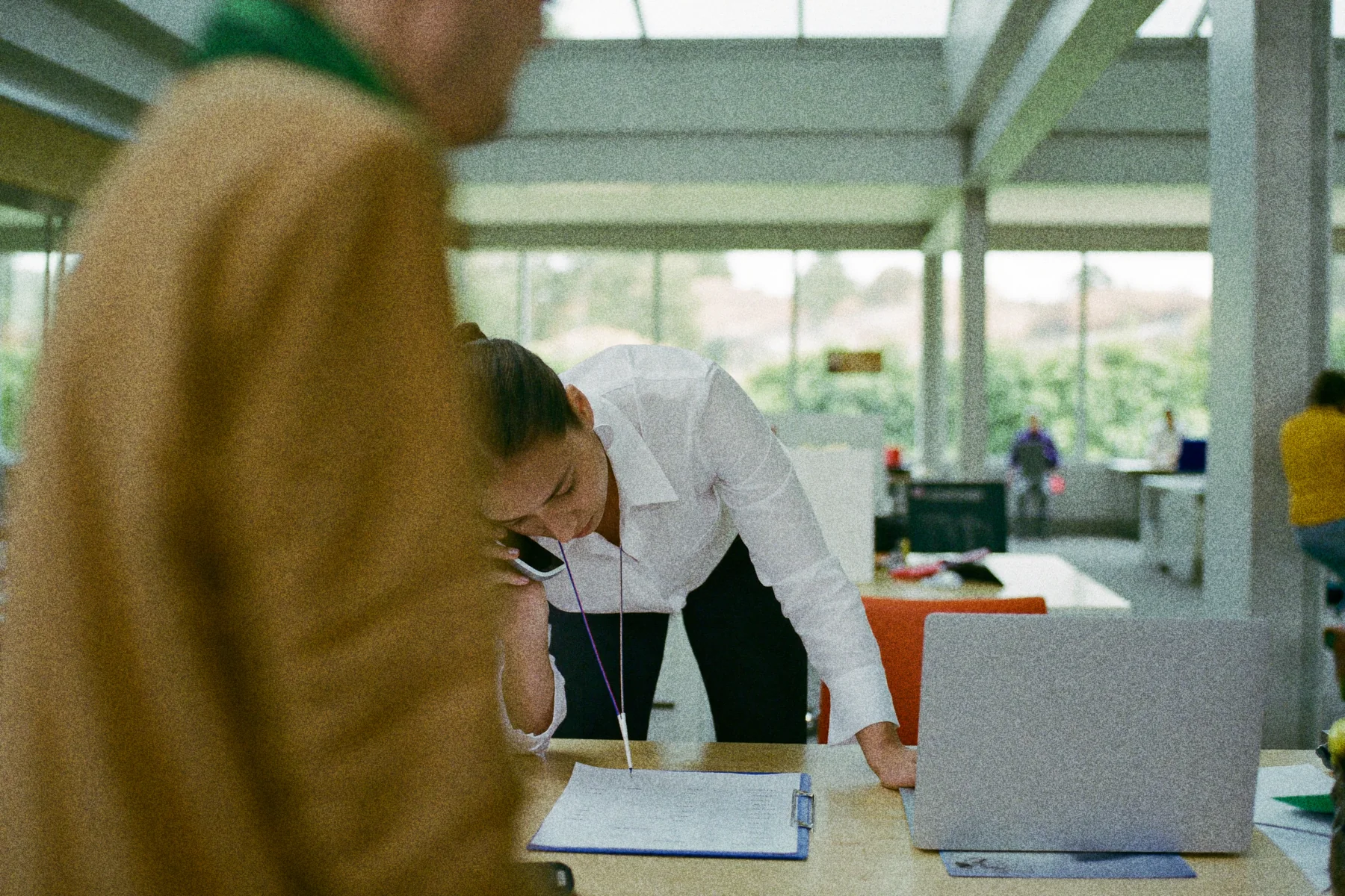 Een administratief medewerker controleert een checklist op zijn bureau terwijl hij telefonisch een aanvraag doet.