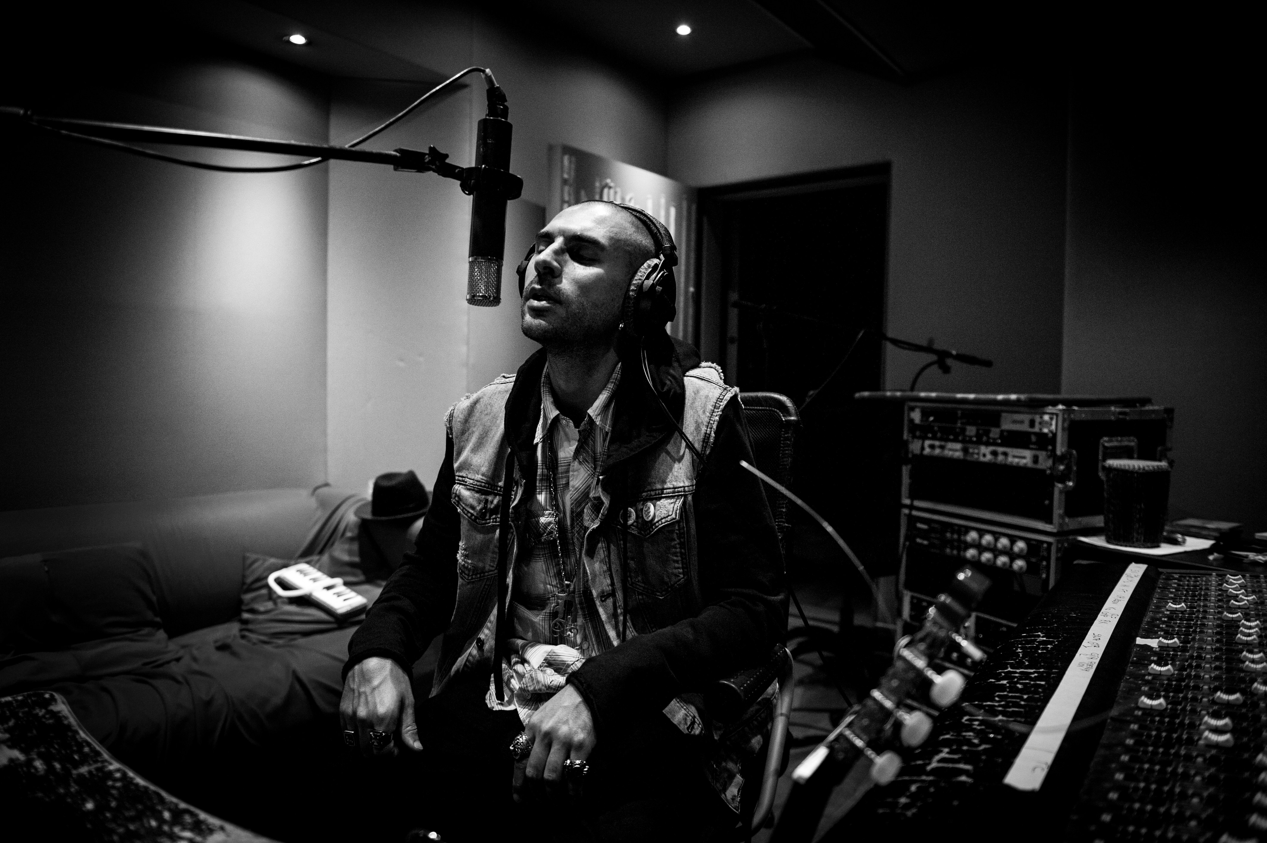 Man sitting in front of a microphone singing in a recording studio