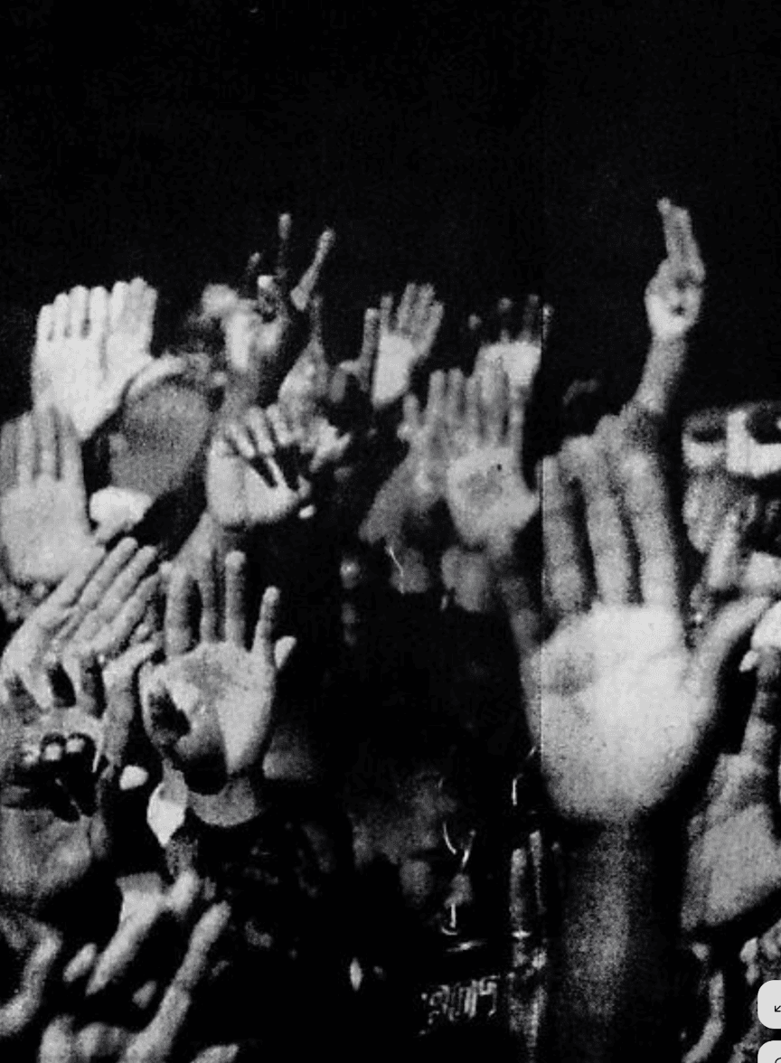 A close-up of raised hands in a crowd, emphasizing excitement and engagement in a lively atmosphere.