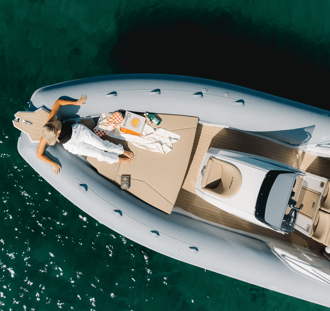 A winding road cuts through rocky terrain, surrounded by patches of green grass and illuminated by sunlight.