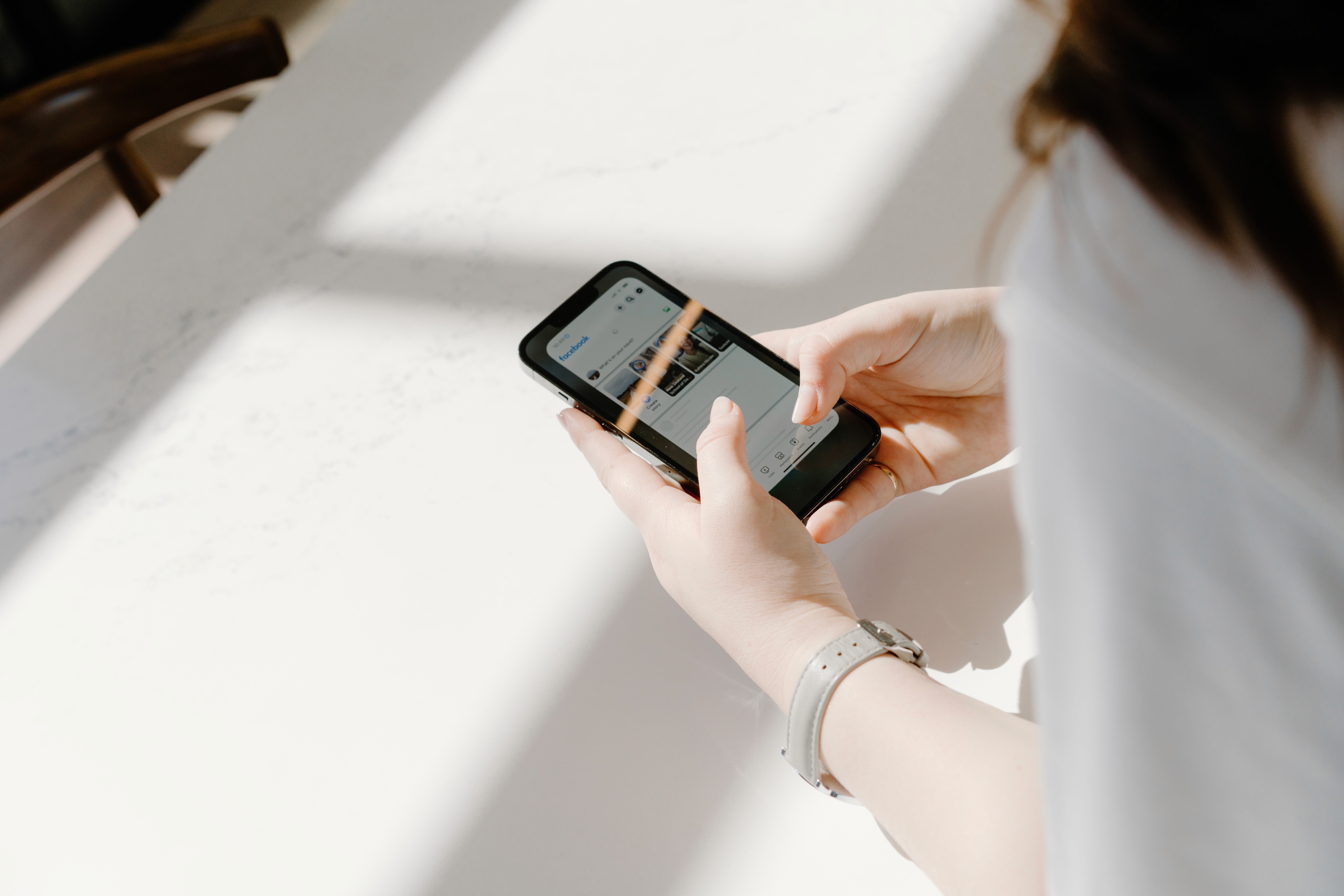 Hands holding a phone with the Facebook app open
