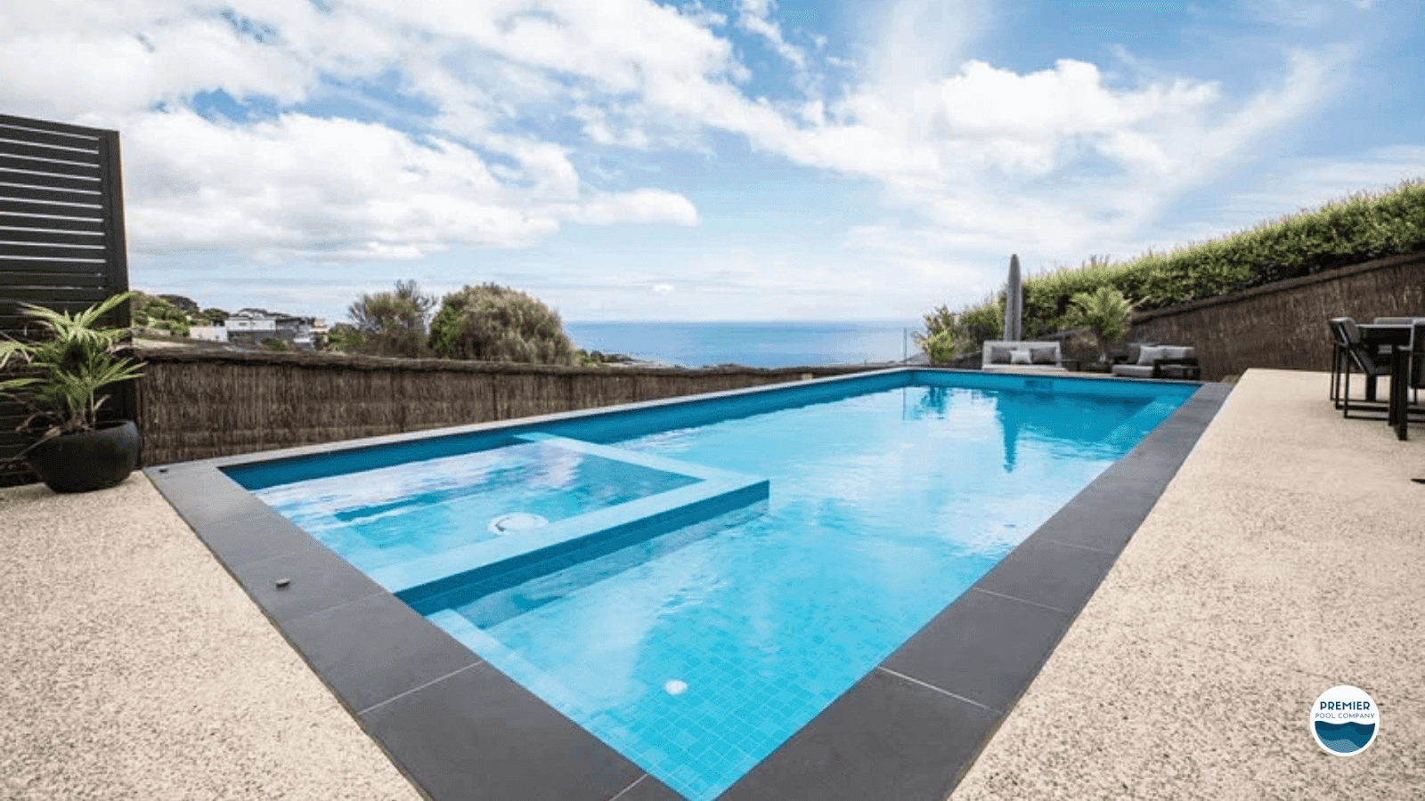 Modern inground fiberglass pool with built-in spa and ocean-view patio, showcasing a high-end backyard design for cost comparison