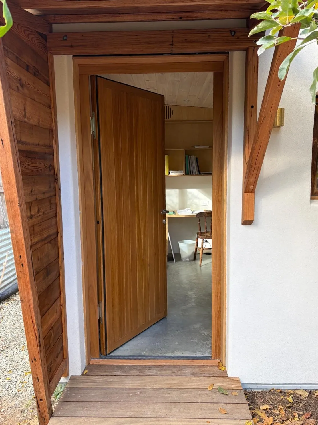 Open timber door of the hempcrete backyard studio in Canberra, looking into the home office with a concrete floor