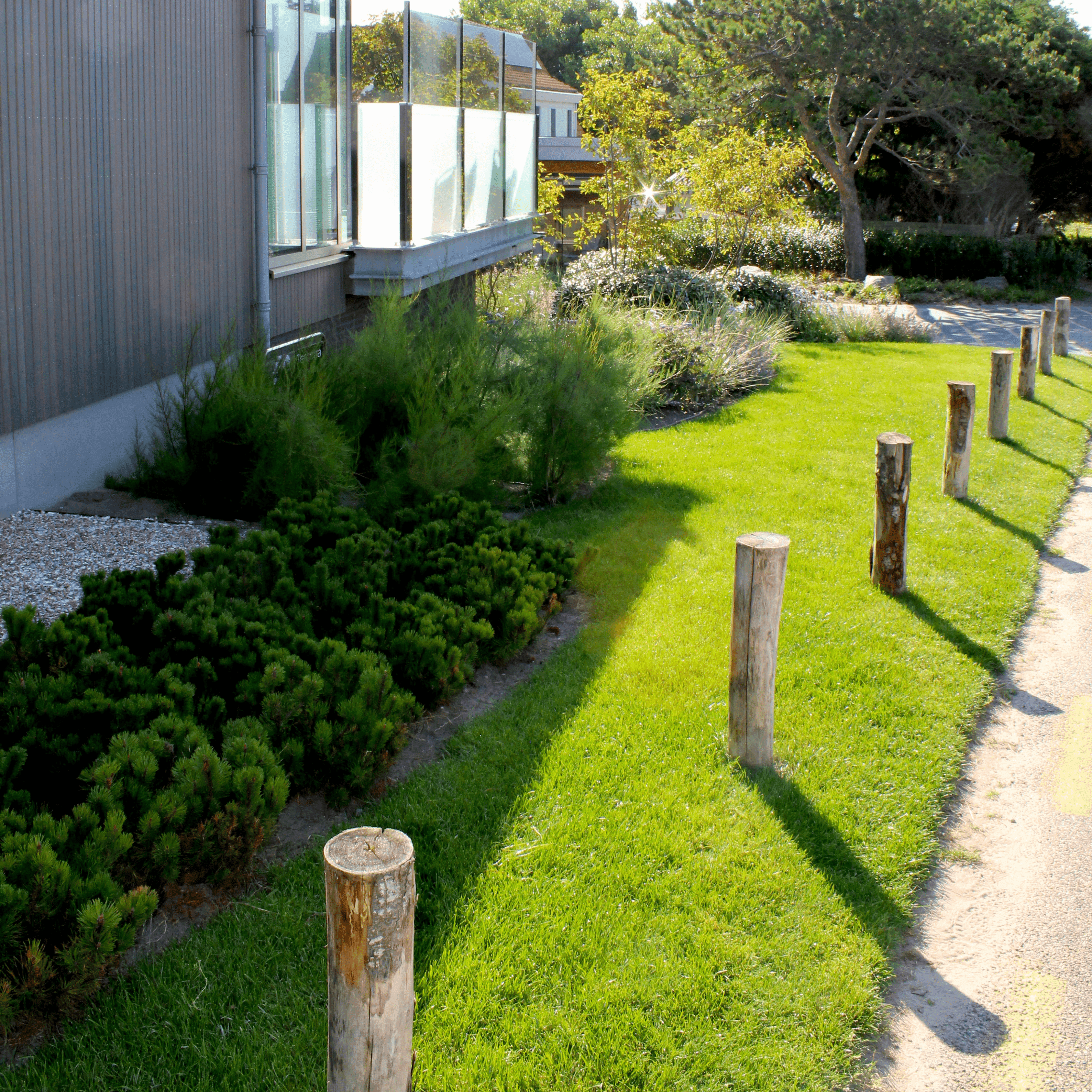 Modern staircase with wooden steps and black railing, decorated with hanging gold lights. Bright white walls feature abstract art, creating a sleek, airy ambiance.