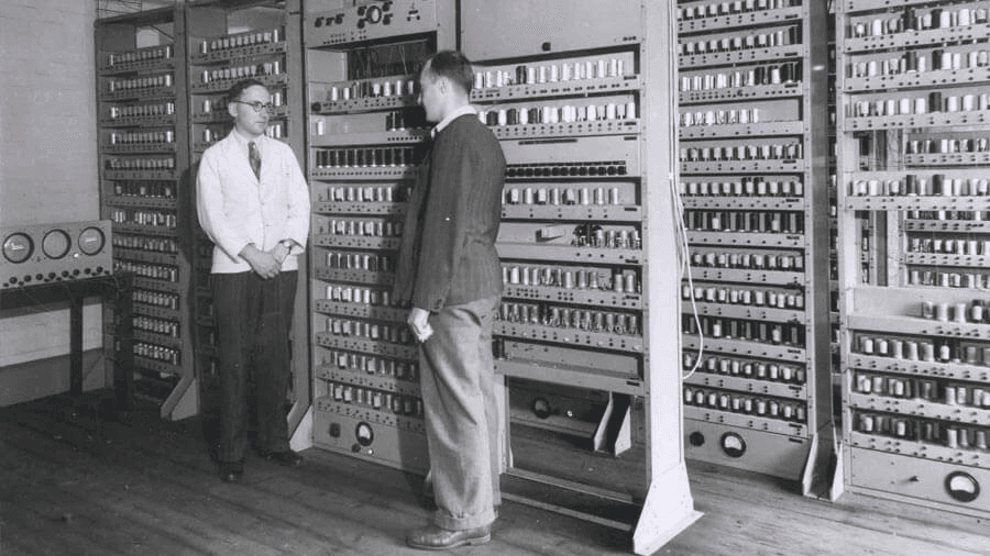 Men standing with an old computer
