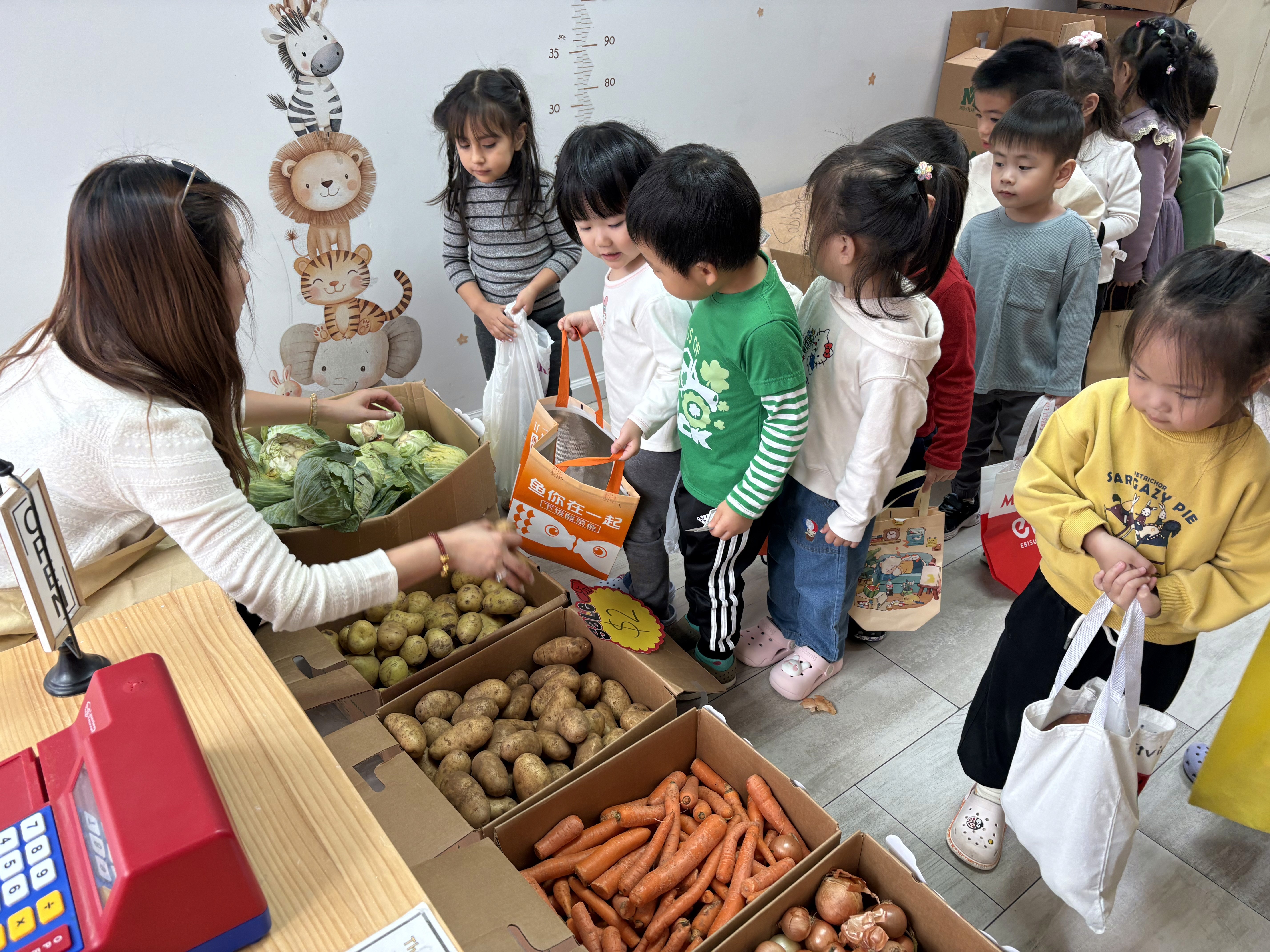 Young students pretend shop for produce at a Fall Harvest Market.