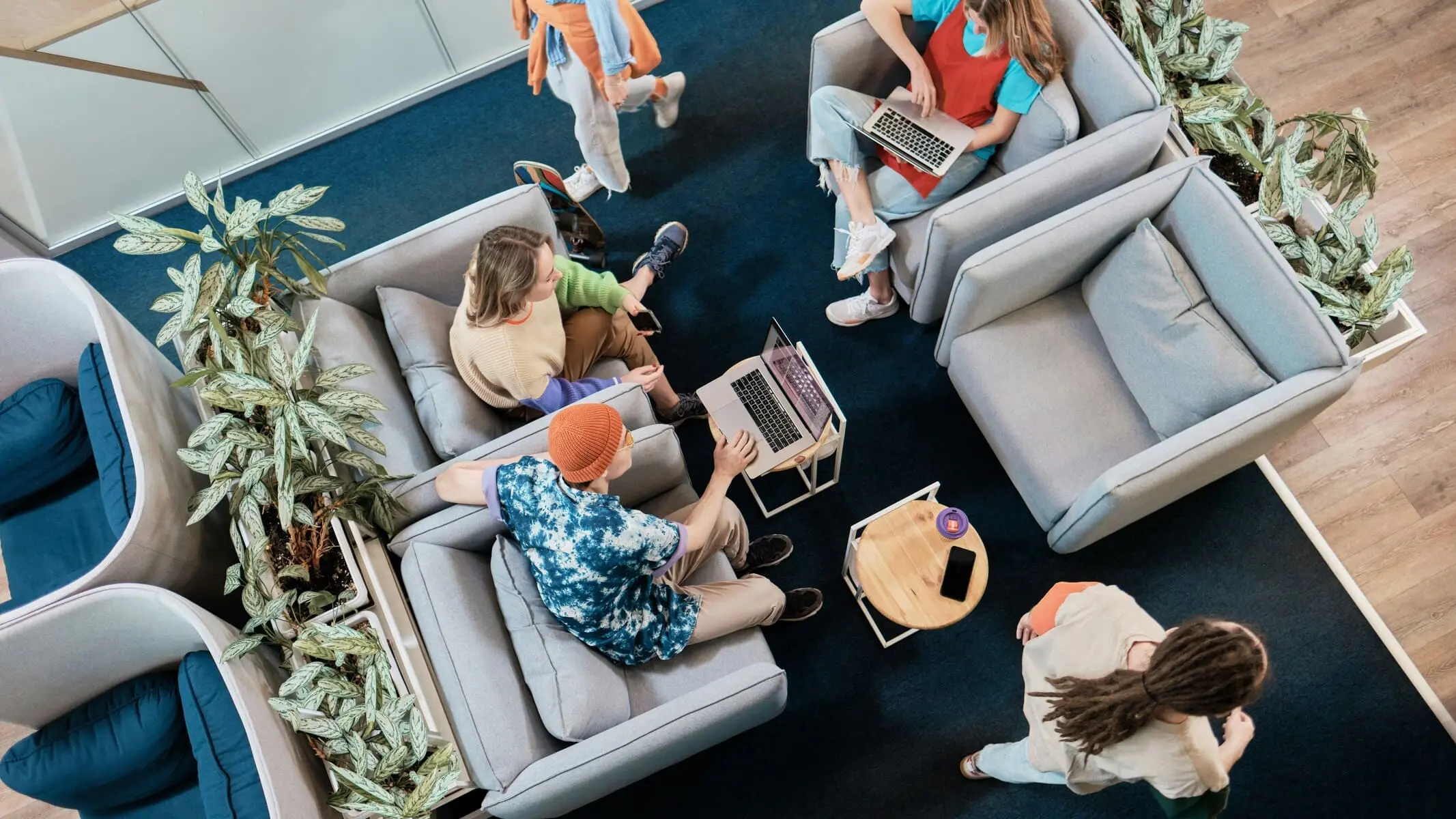 Top-down view of a team of young people sitting casually on chairs, working together with their laptops.