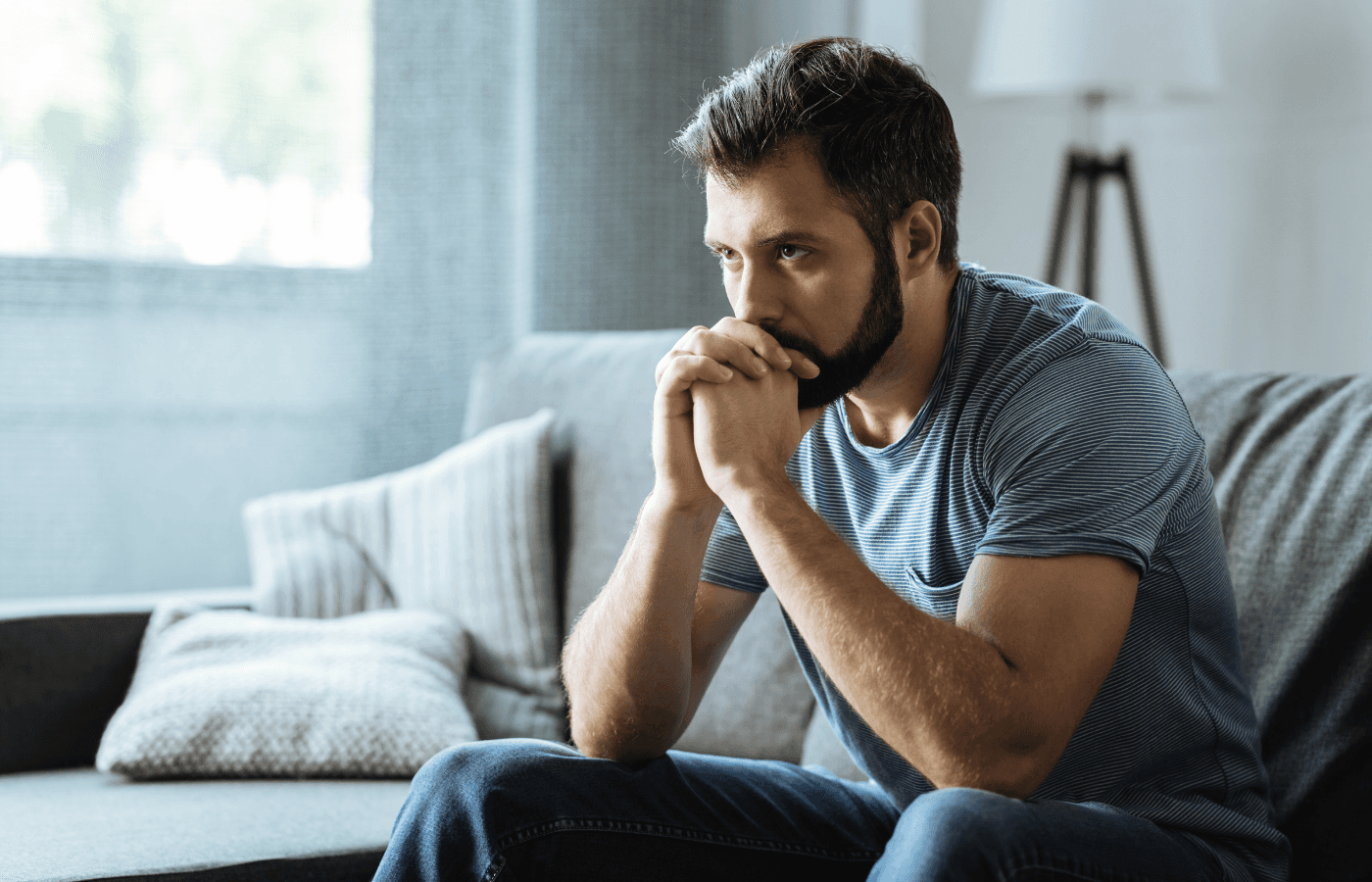 bearded man sitting on the sofa deep in thought