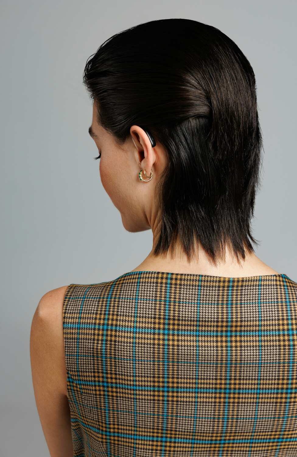 A woman with her back to the camera, she's wearing a hearing aid.