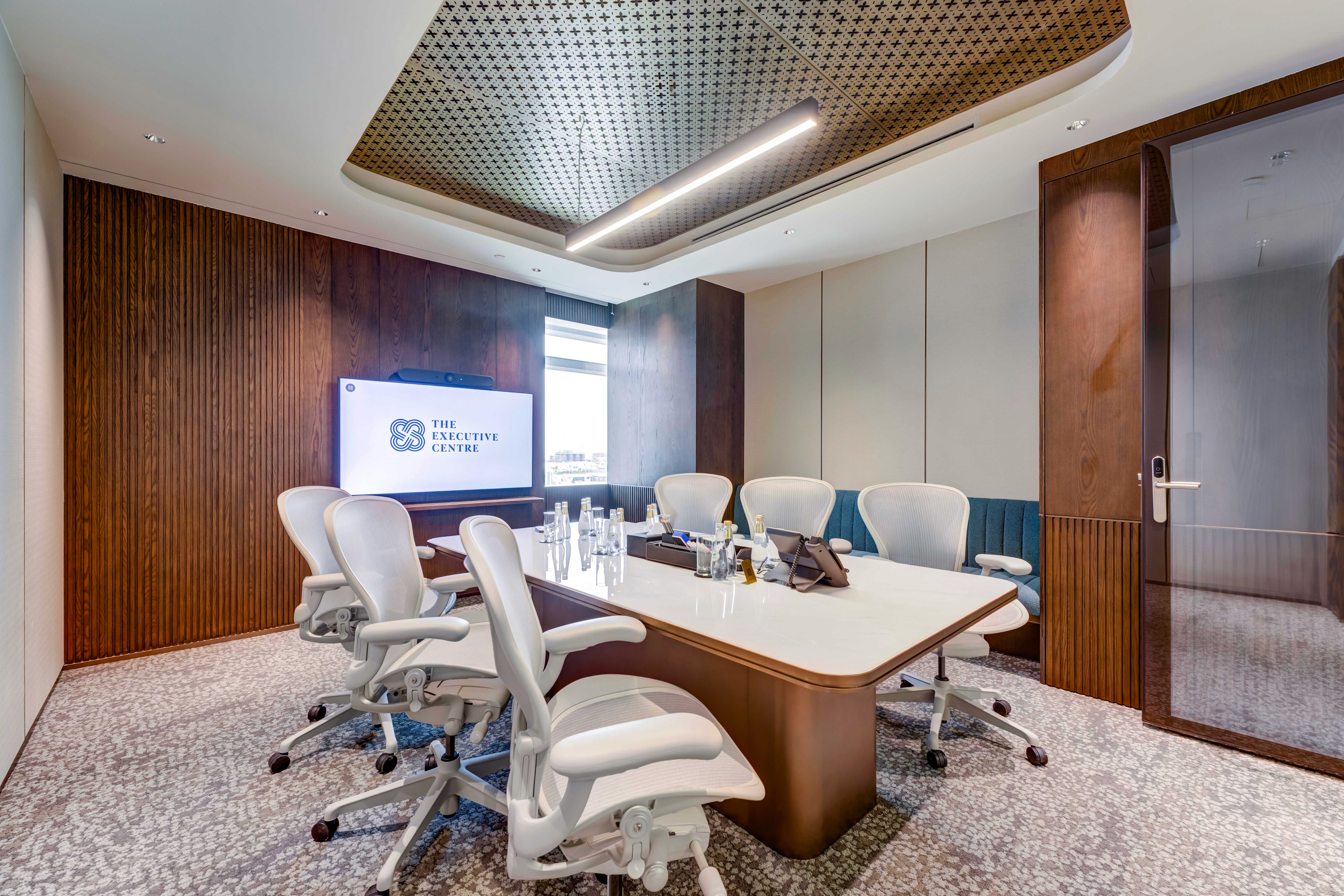 Executive boardroom featuring a large screen, comfortable seating, and wood paneling.