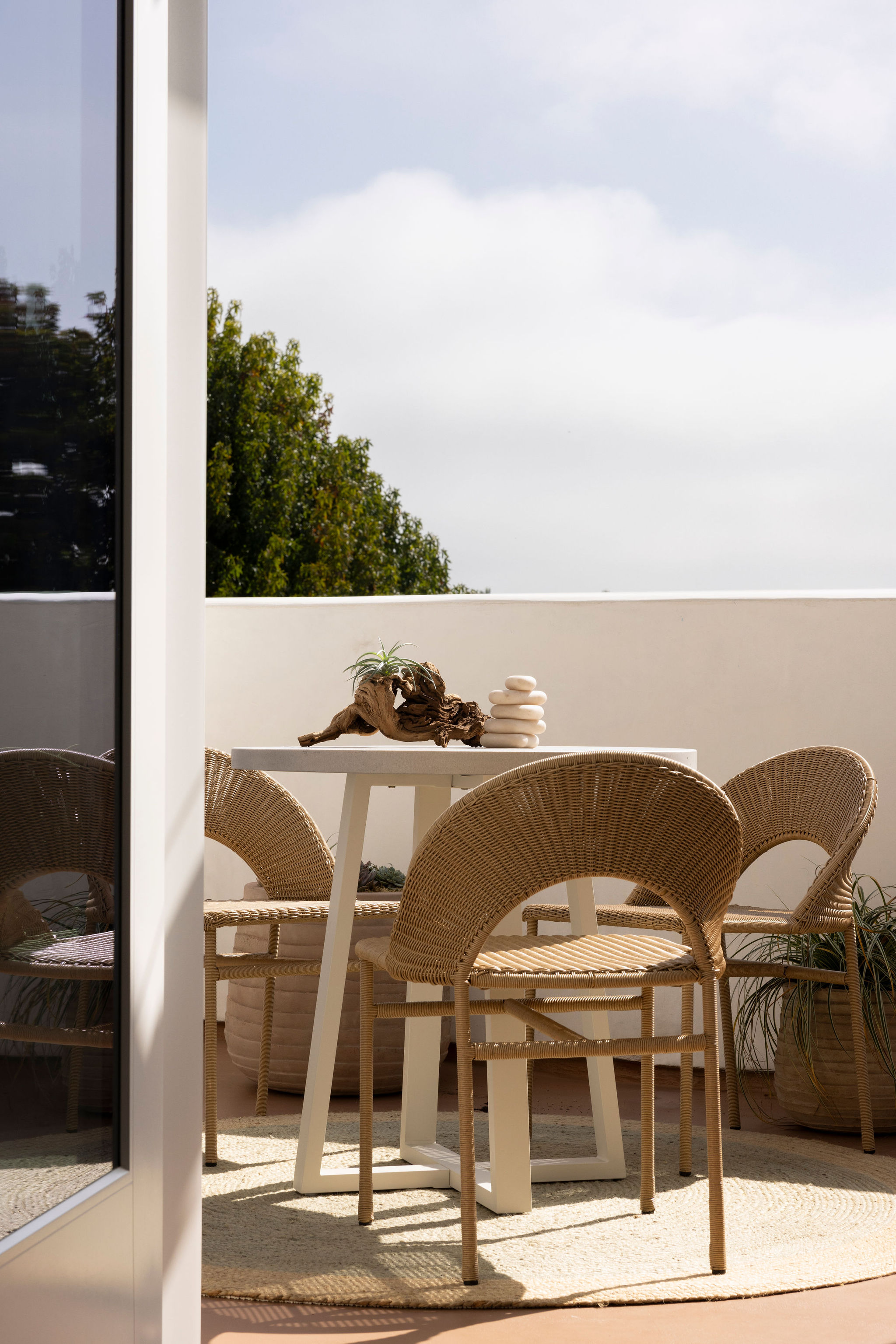 Inviting outdoor balcony off the dining area with comfortable seating, lush potted greenery, and serene coastal views for days.