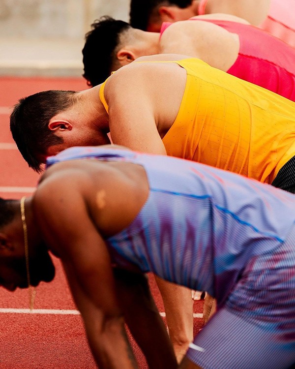 braided woman taking photo beside yellow painted wall