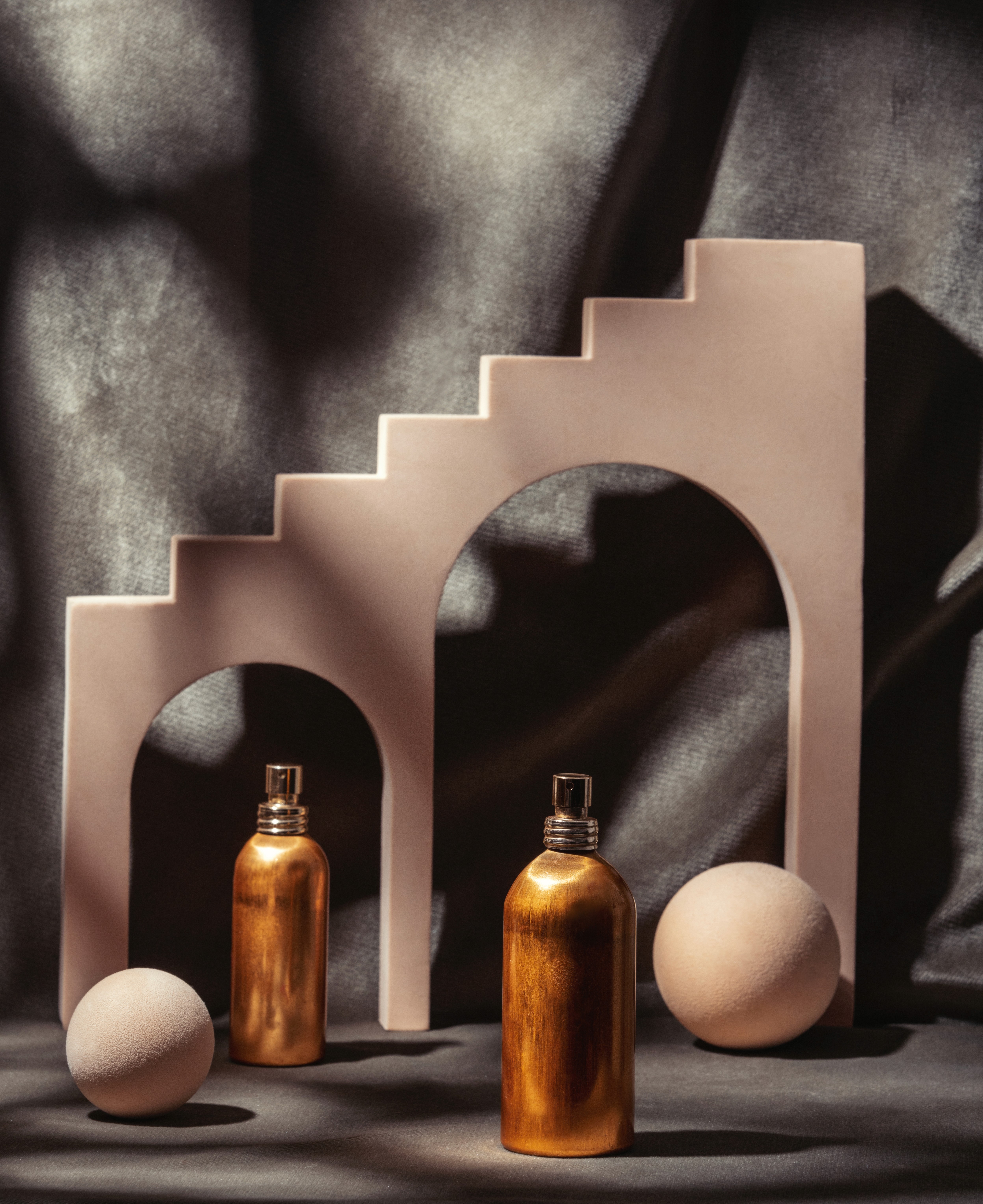 Two smiling models in close-up portrait, one with dark curly hair and burgundy lipstick, one with dark bangs and freckles, wearing black turtlenecks