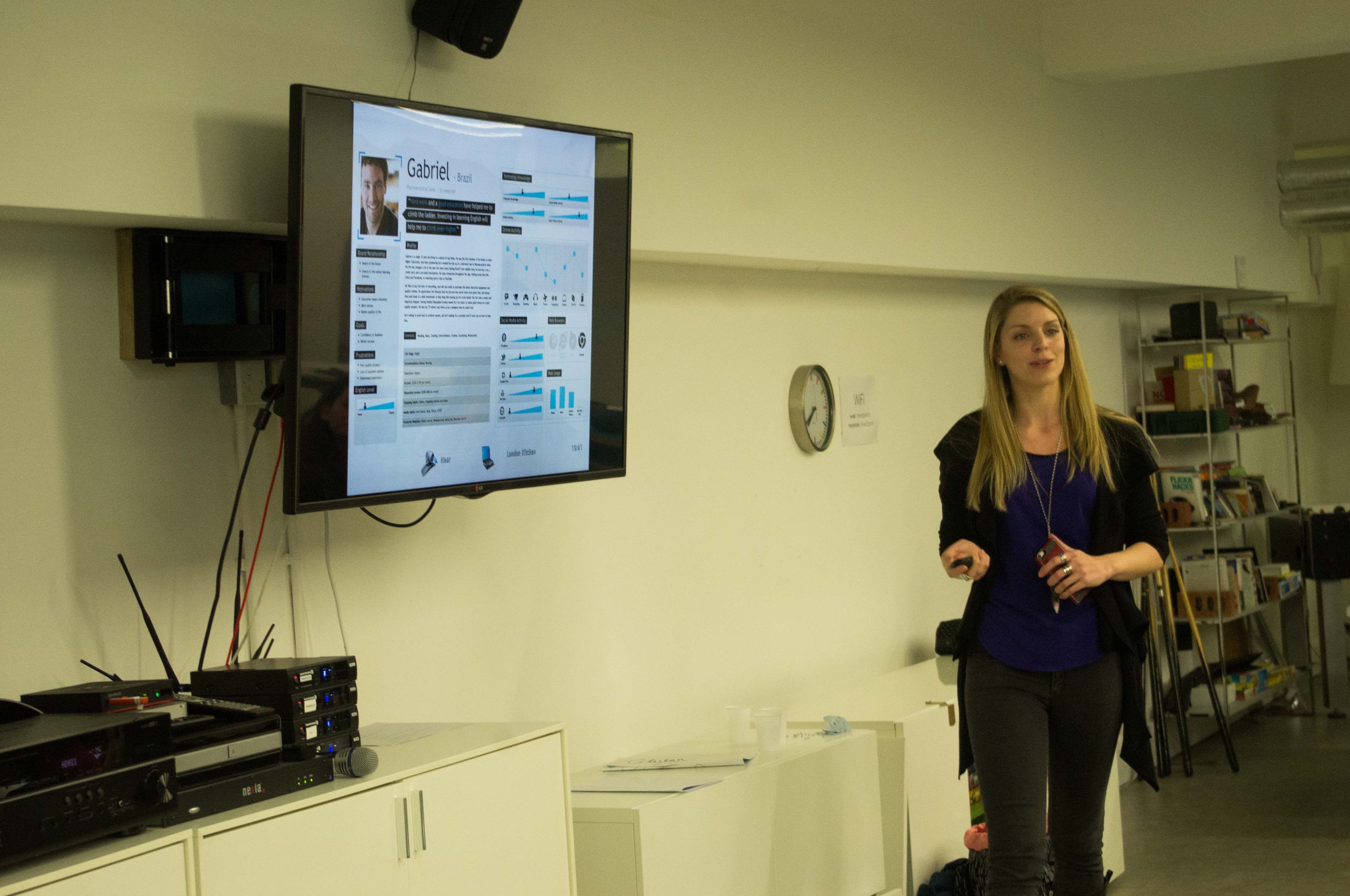 Samantha standing next to a monitor, speaking at an event.