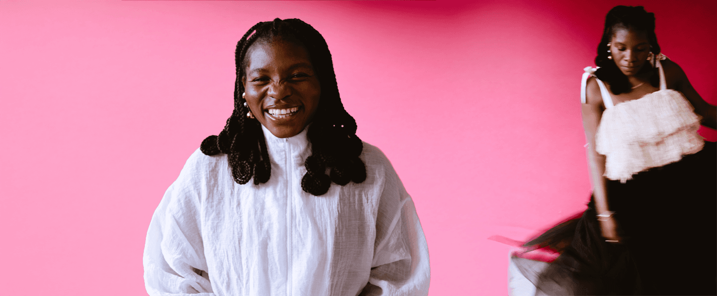 Dali Adekunle sitting and smiling and in the background dancing with pink and red wall to connect with