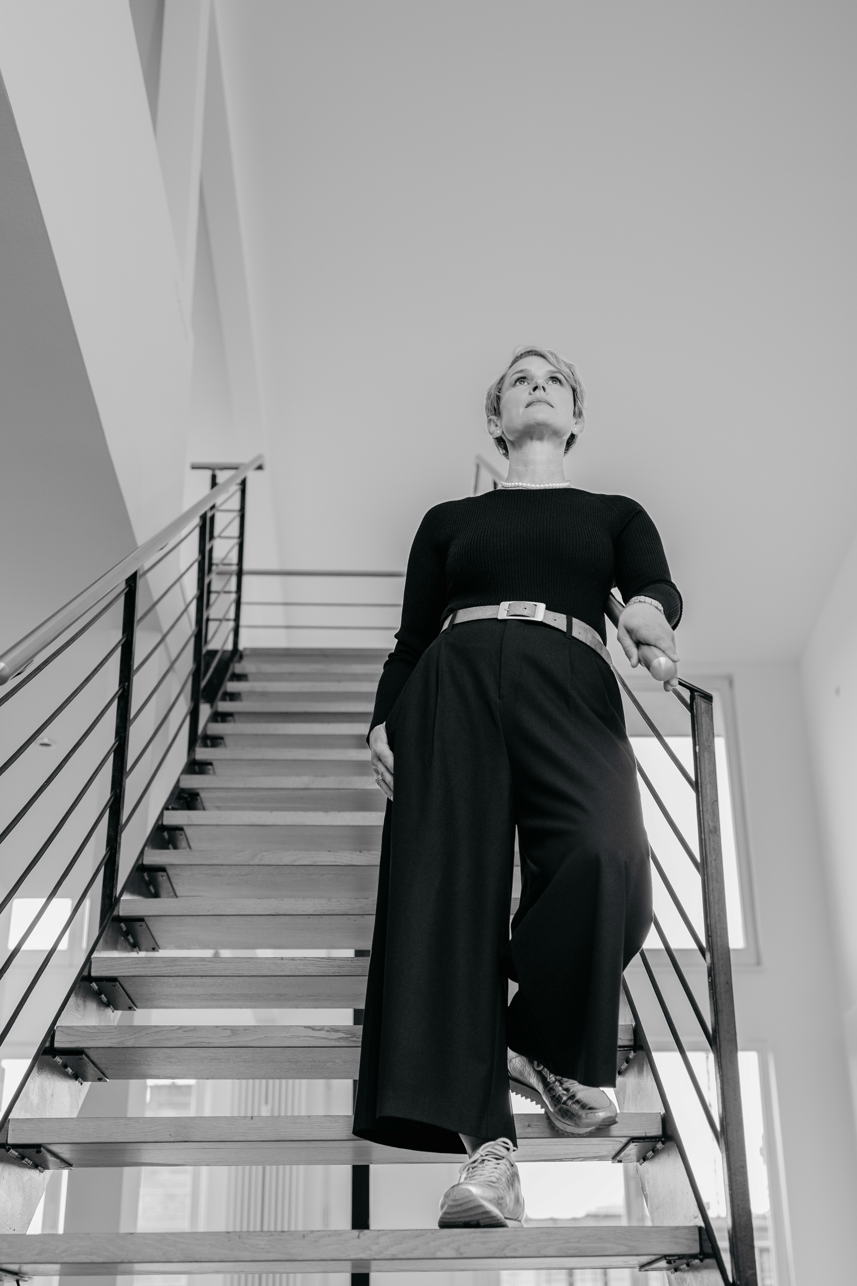 Nathalie Bourgeon geht eine Treppe hinunter, aus der Untersicht aufgenommen, mit klarer und selbstbewusster Haltung