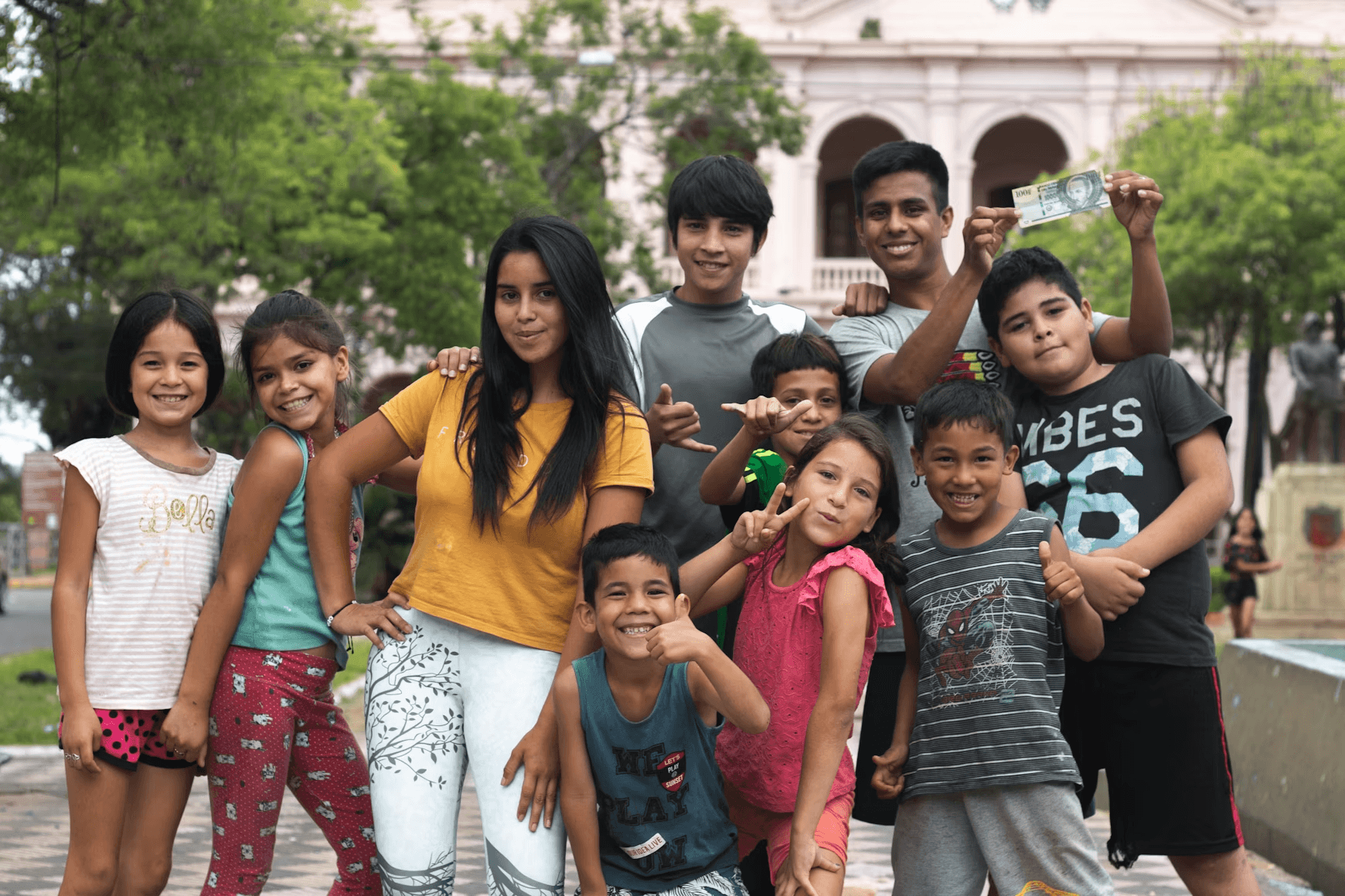 Group of children posing, one holds money