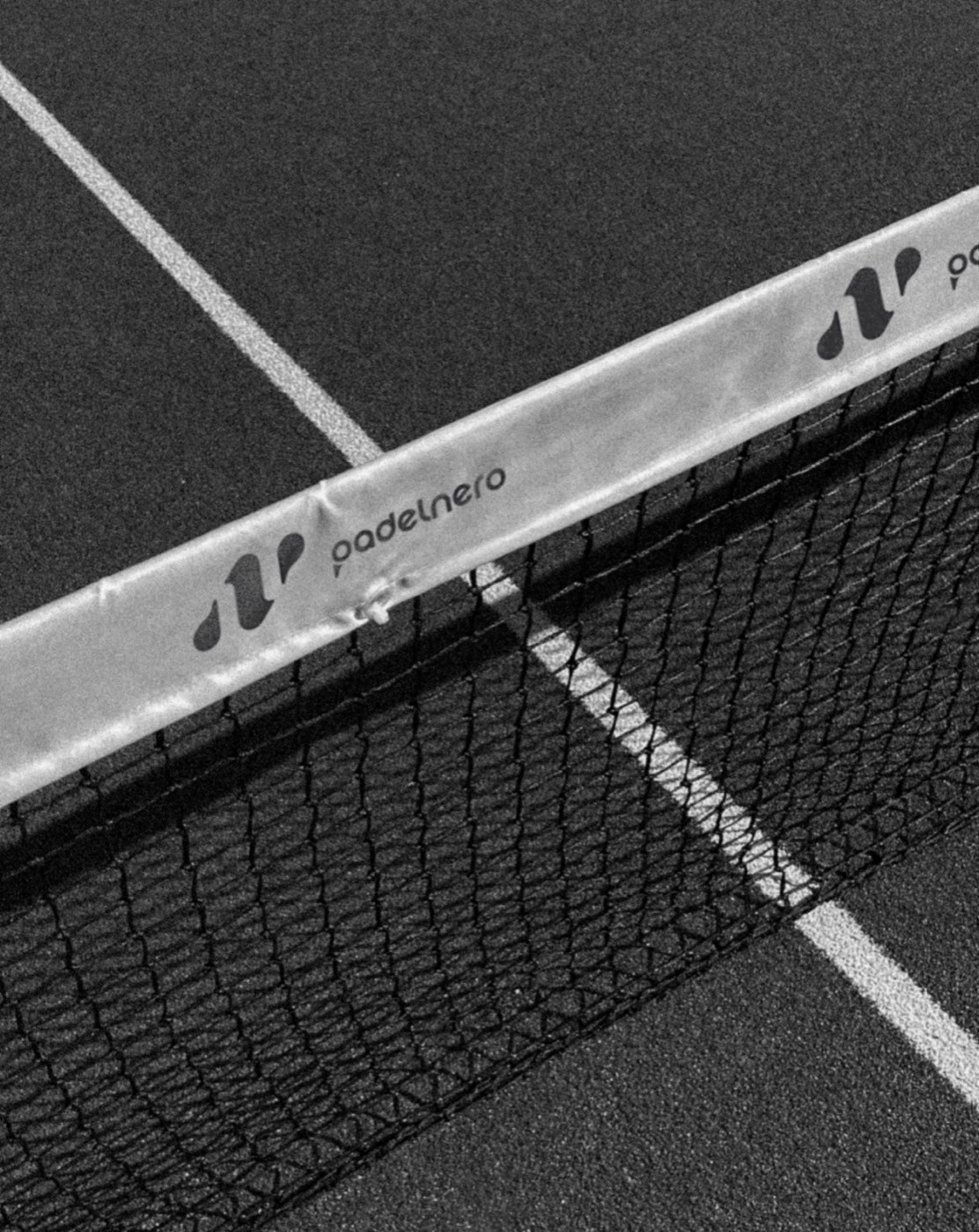 Schwarzer Padelplatz mit Netz und Padelnero-Logo auf der Netzbande.
