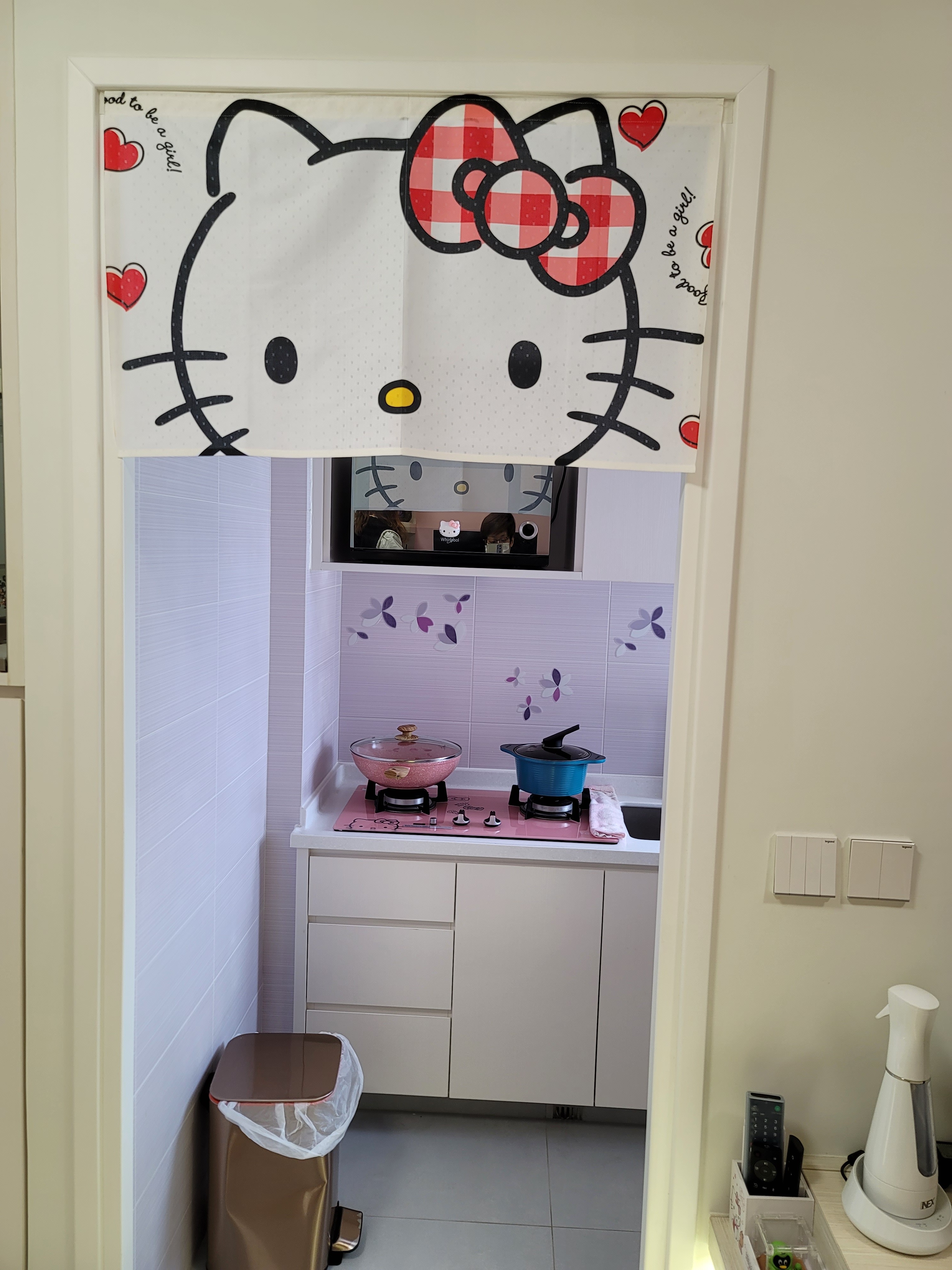 > This modern Hello Kitty kitchen interior design at Hoi Tat Estate features built-in cabinetry finished in premium Farrow & Ball paint and a seamlessly integrated washing machine, effortlessly blending playful character into a crisp, minimalist aesthetic framework.