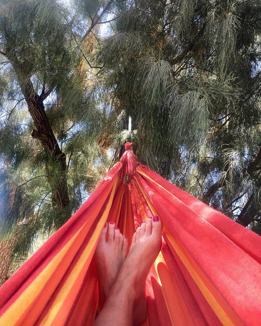 A model dressed in a mustard yellow blazer and cream trousers poses confidently against a minimalist background with sky blue and beige tones, exuding a modern and chic fashion aesthetic.