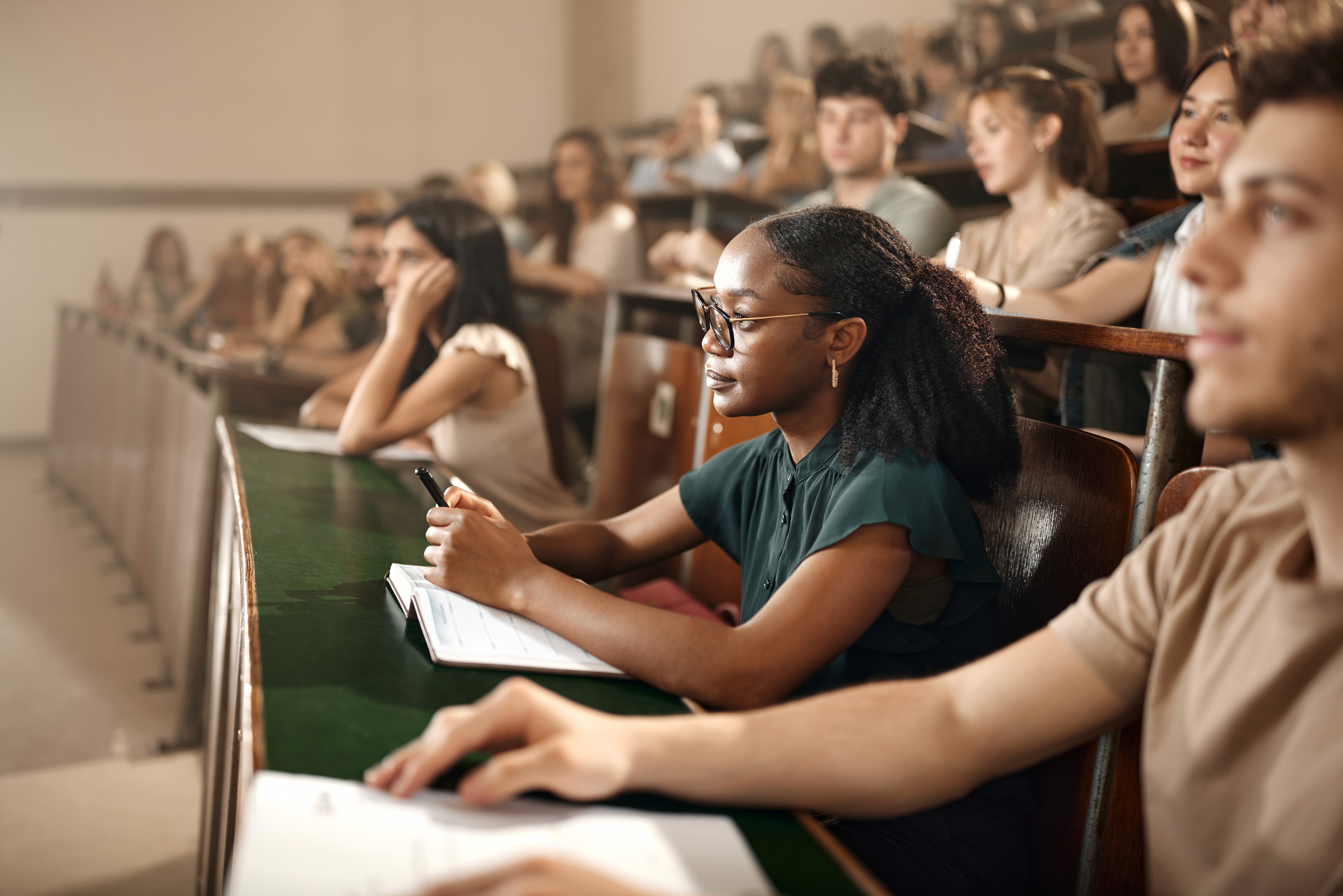 Smiling businesswoman shaking hands with someone across a table in an office setting.