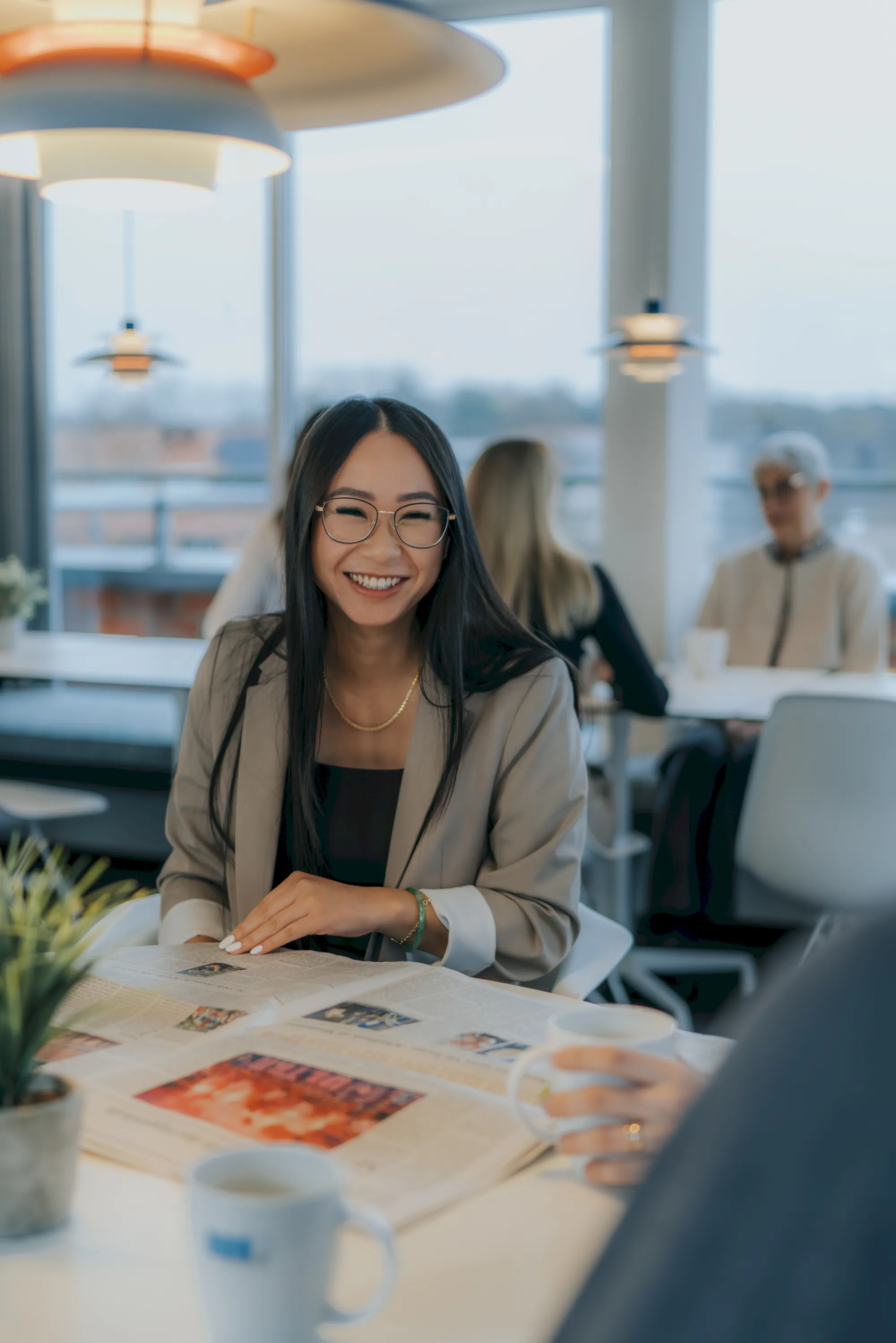 Fröhliche junge Frau mit Brille im Büro, lächelt in die Kamera